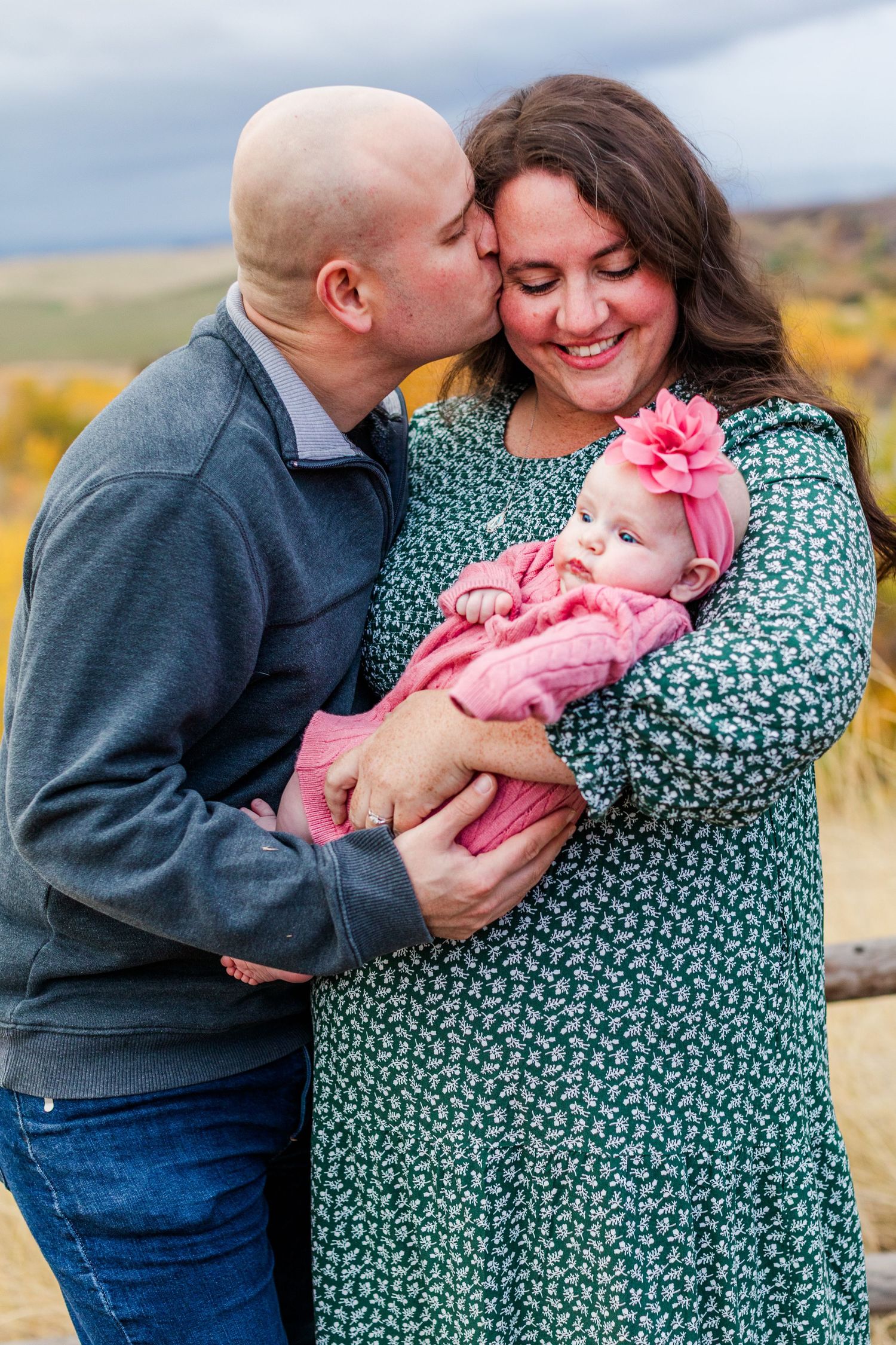 A green floral dress stands out during an intimate family moment in golden grass.