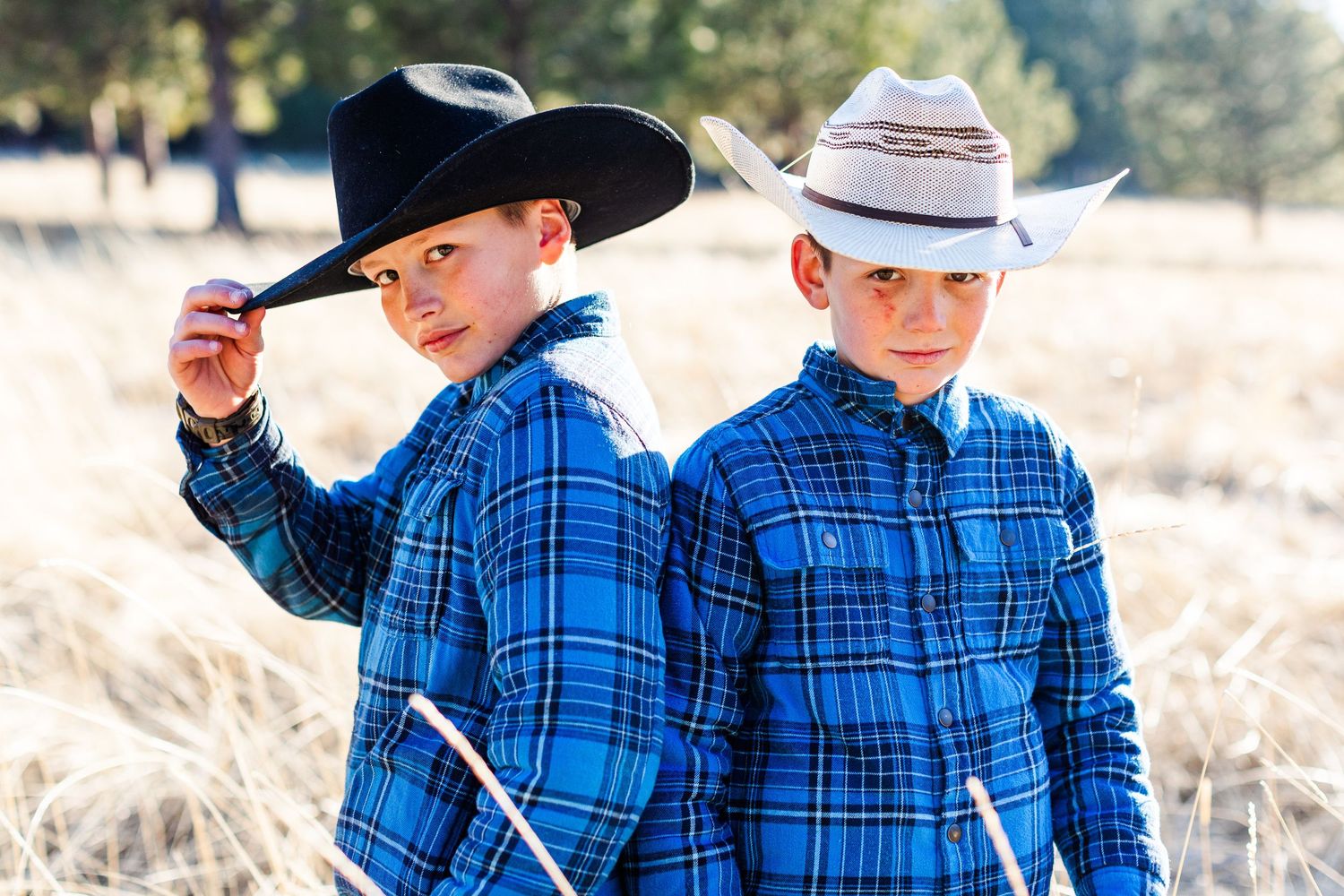 Western-themed portrait of two people in matching outfits against natural outdoor backdrop.