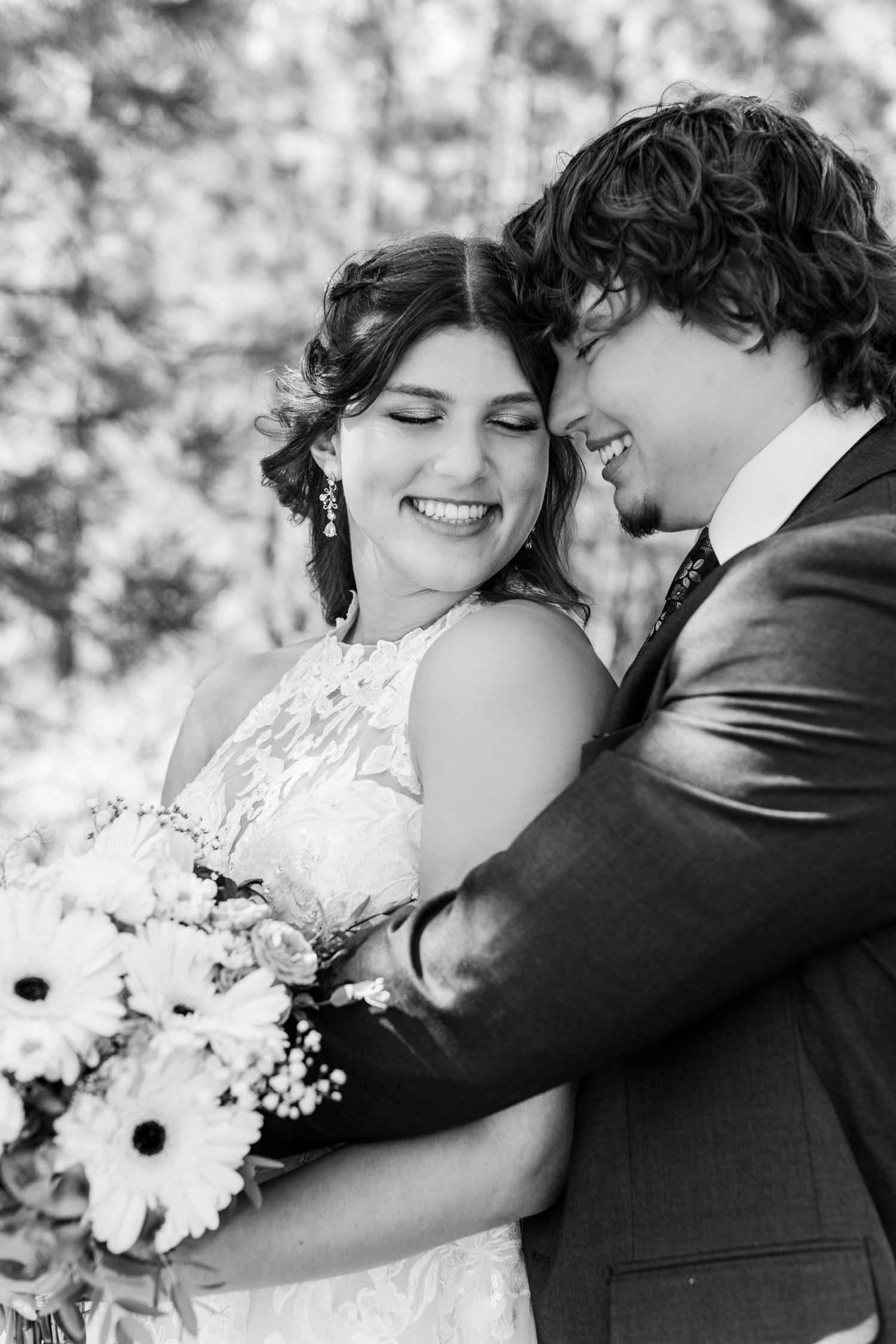 A romantic black and white photo series of a couple embracing on their wedding day with white flowers.