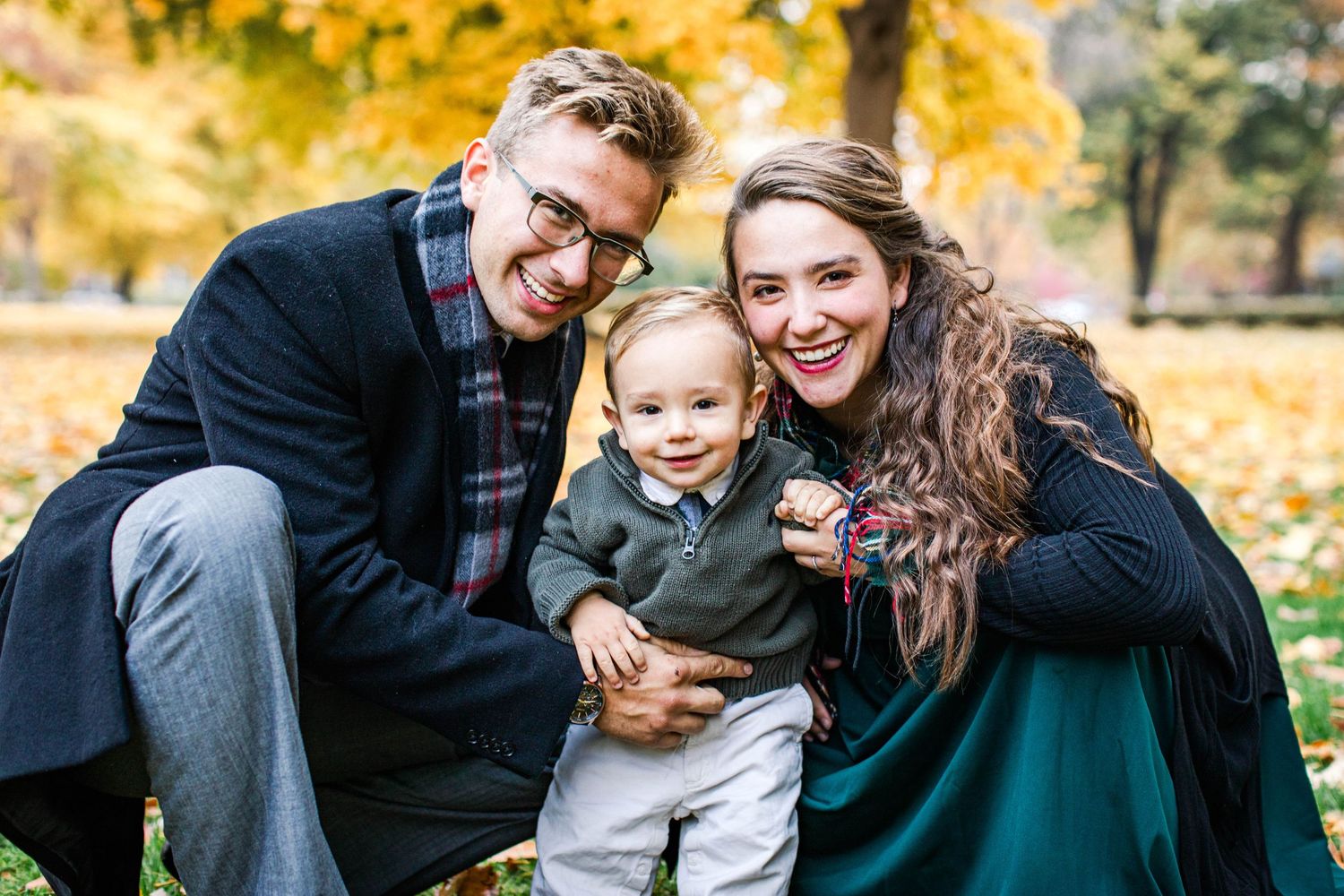 Joyful autumn family portrait with fall foliage in background.