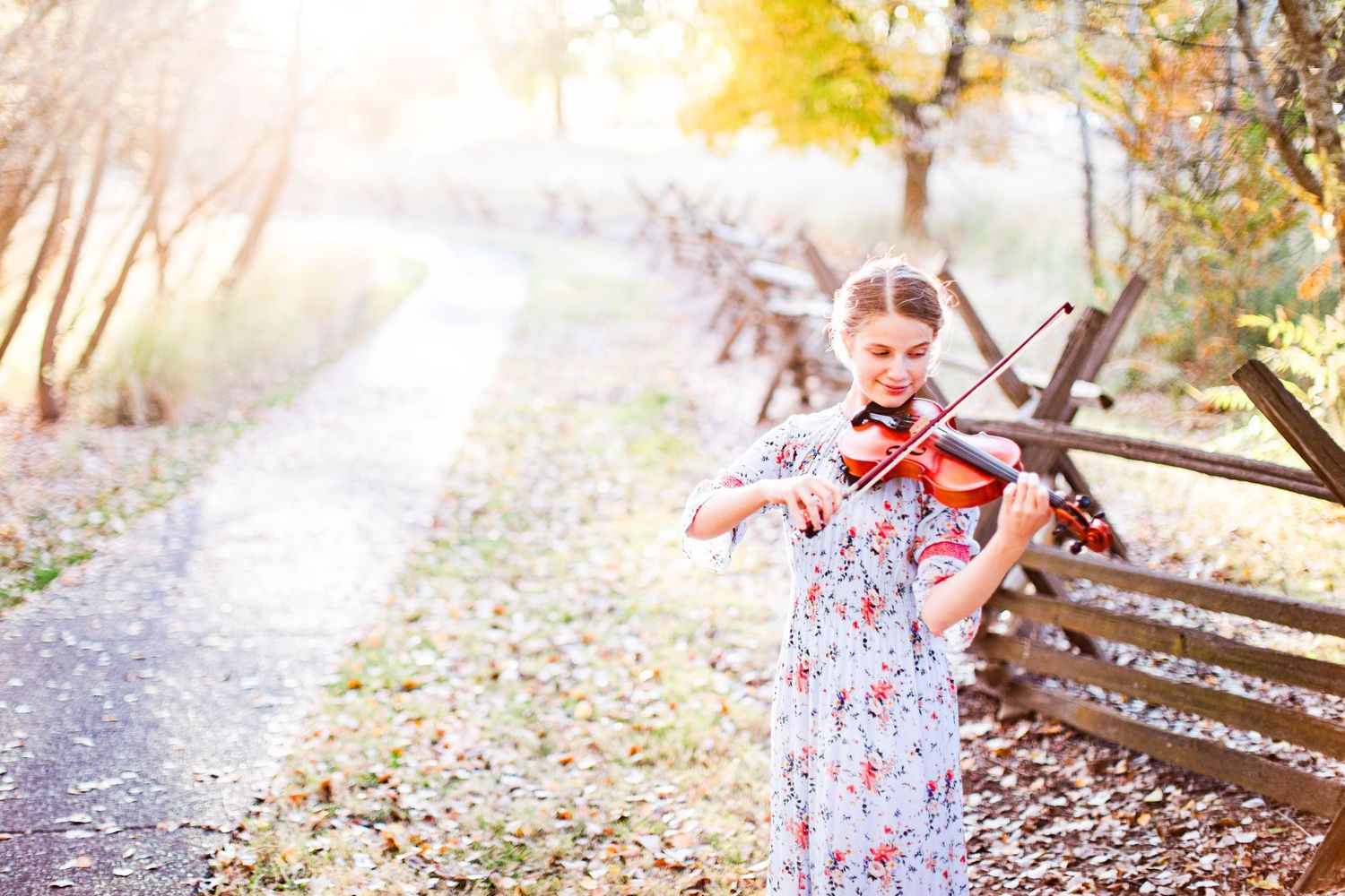 Multiple shots of a violinist playing outdoors in a floral dress.