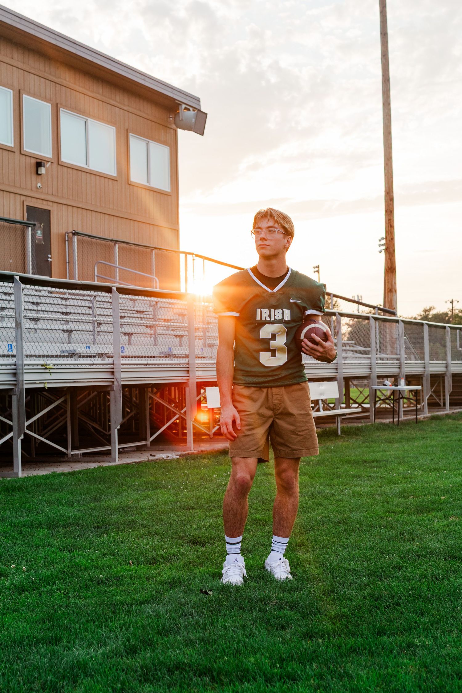 Football player in Irish uniform practices on field during golden sunset.