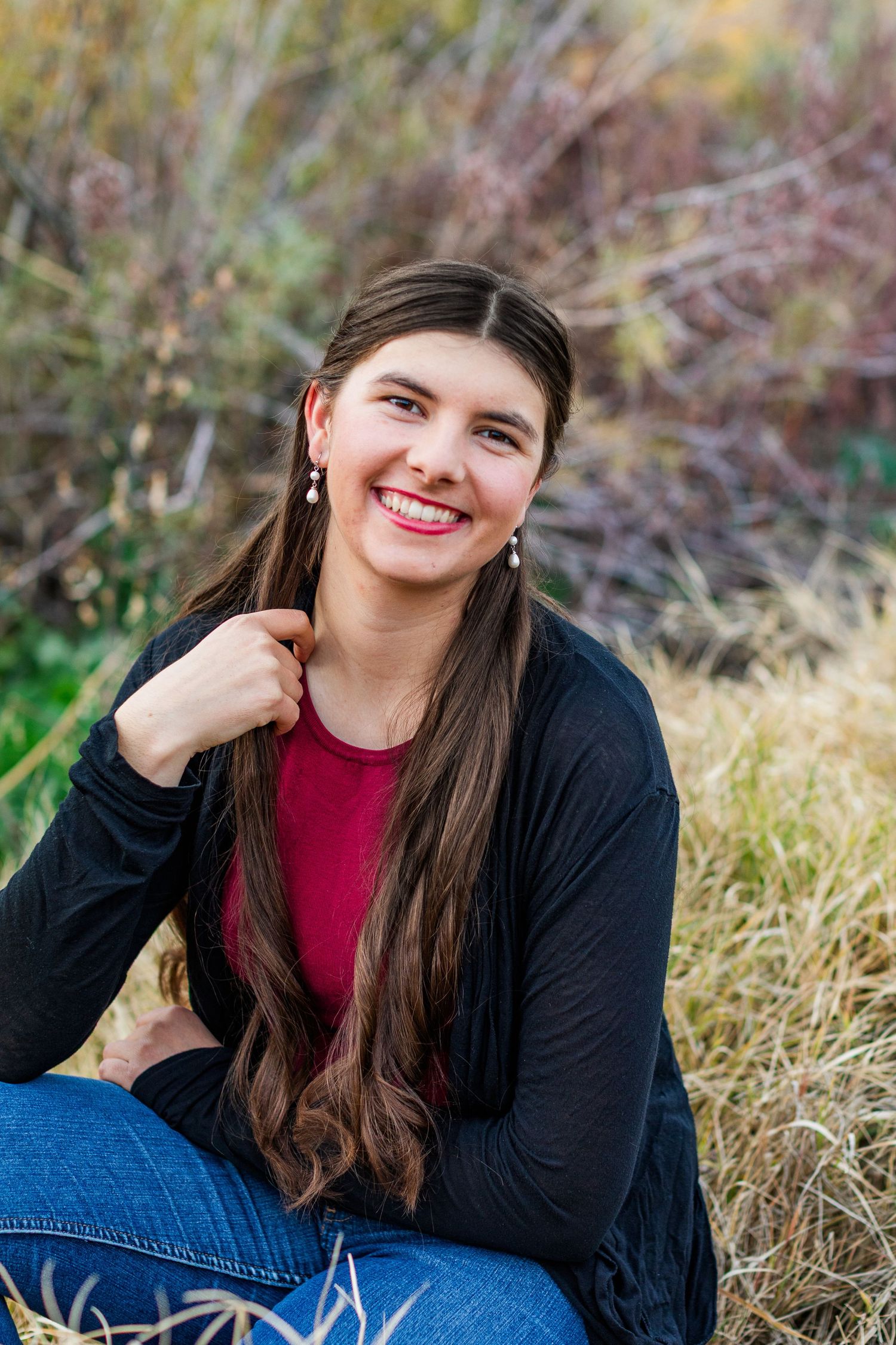 Casual outdoor portrait session in natural grass setting with warm autumn lighting.