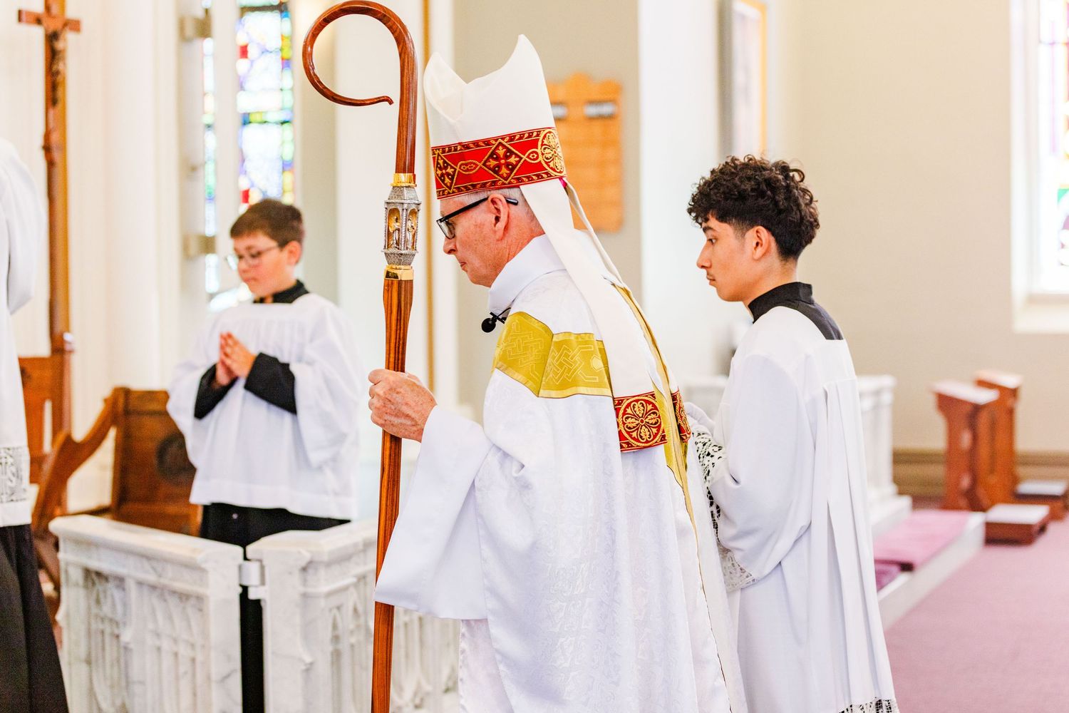 Young altar servers in white robes participating in church ceremony.