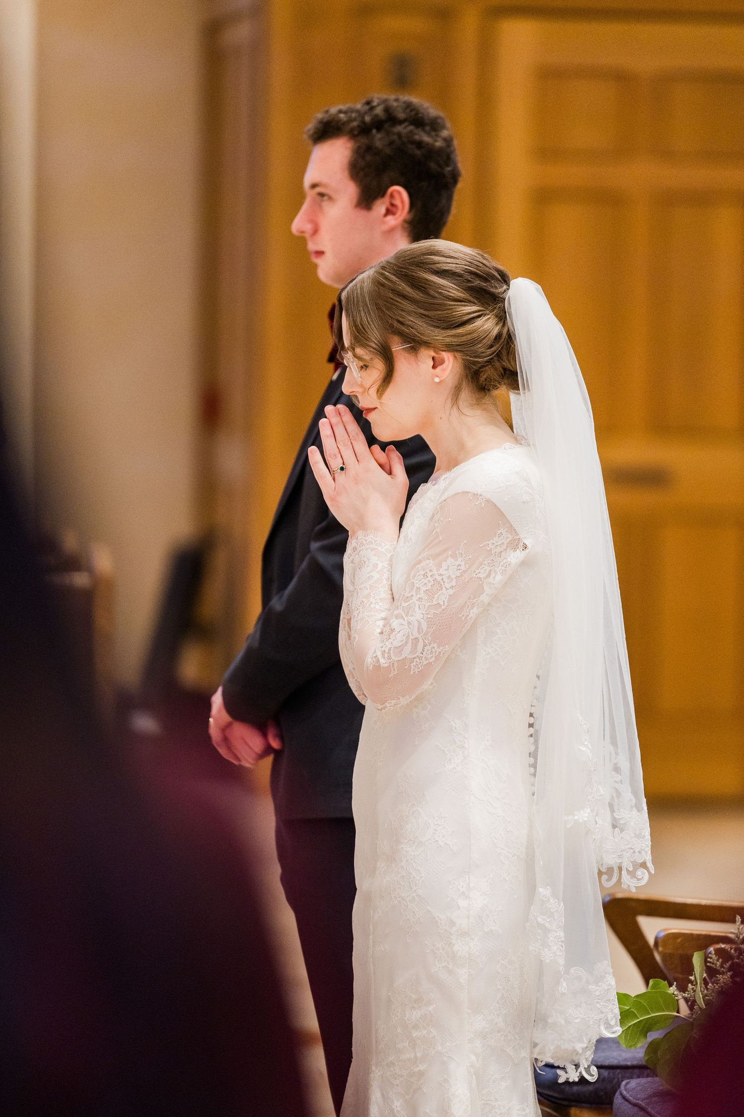 Couple praying together during their wedding ceremony in an ornate church sanctuary.