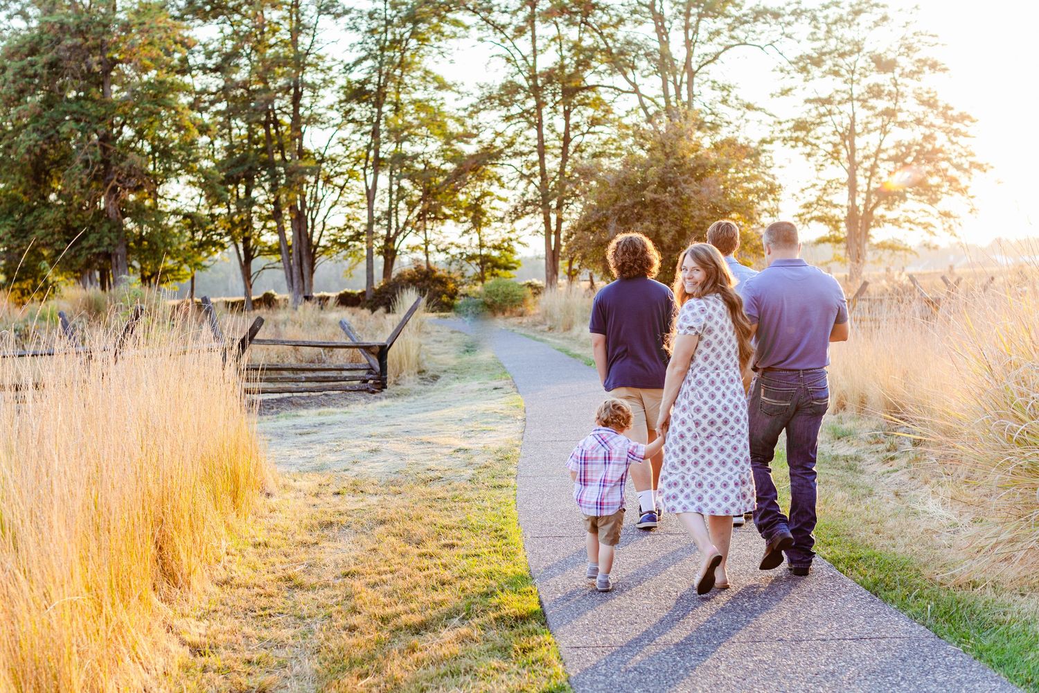 Family walking hand in hand along a scenic path during sunset.