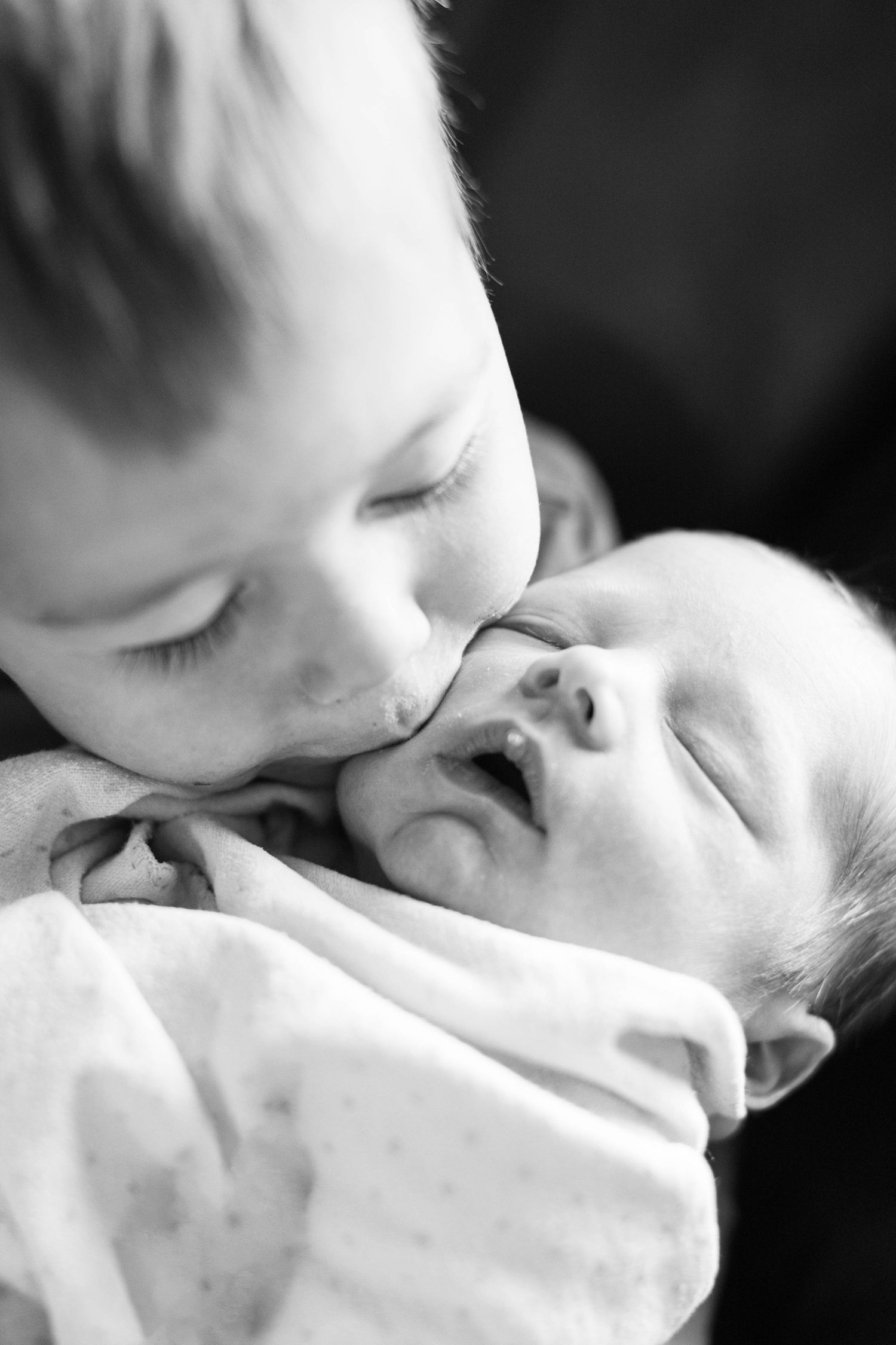 Close-up black and white portrait of sleeping baby wrapped in soft blanket.