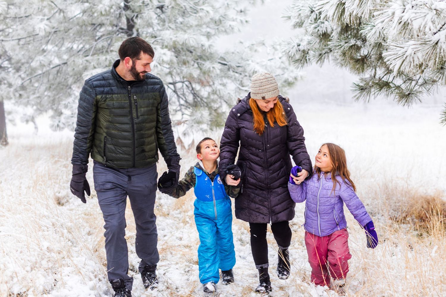 Group walking together through a snowy winter landscape wearing colorful coats.