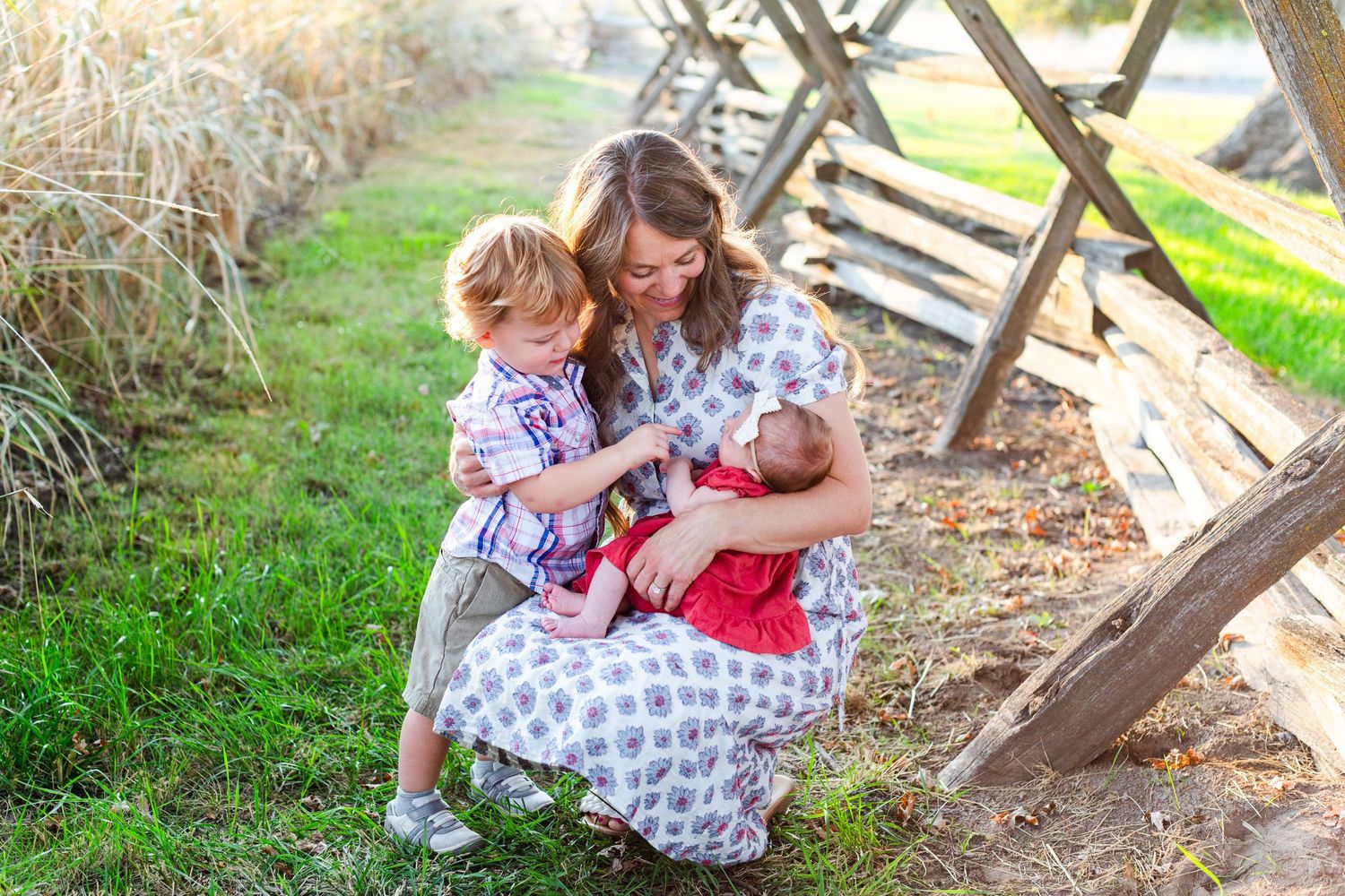 Candid family moments captured in rustic outdoor setting with wooden fencing.