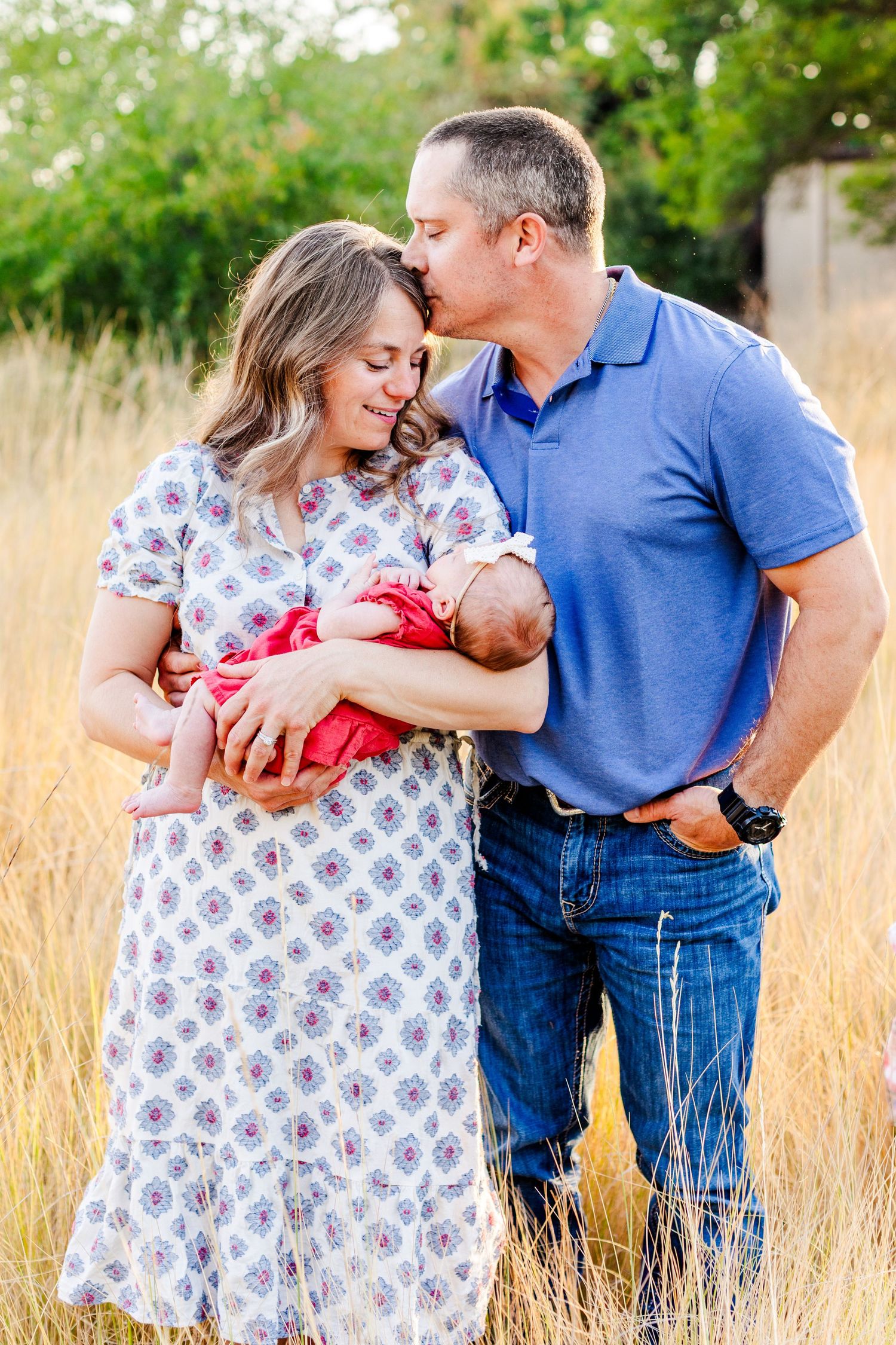 Family sharing intimate moments together in a sunlit meadow with tall grass.