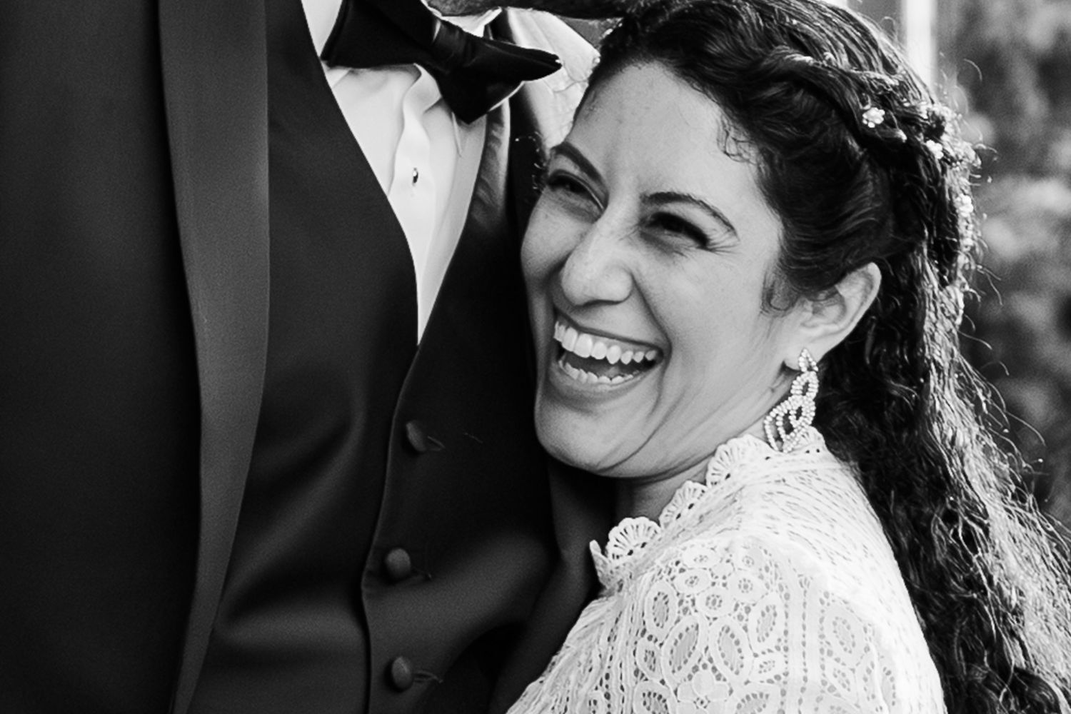 A black and white wedding photo showing a joyful expression and elegant lace dress details.