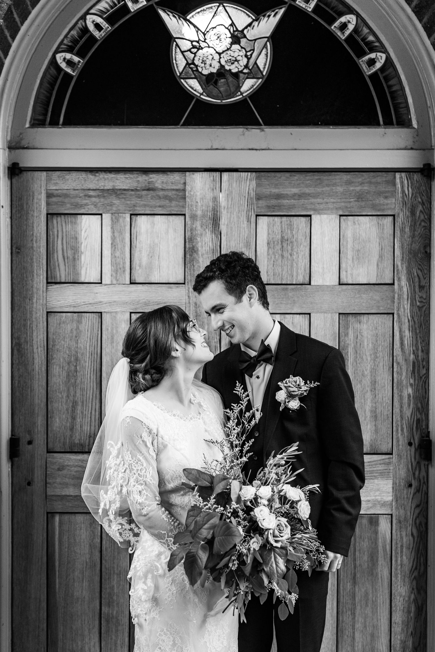 Black and white wedding portraits showing romantic moments between newlyweds against wooden church doors.
