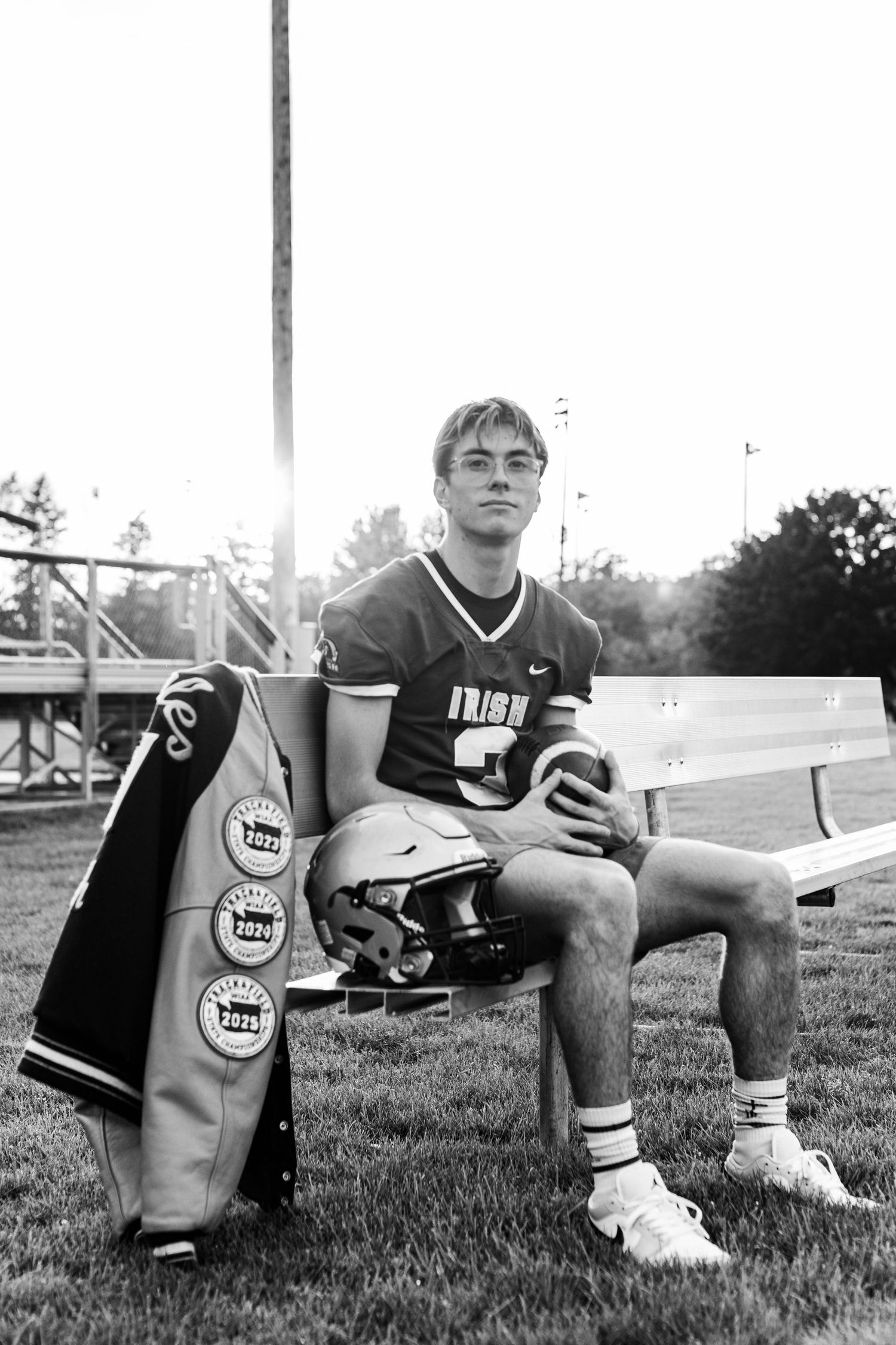 Black and white photo of football player sitting on field with equipment.