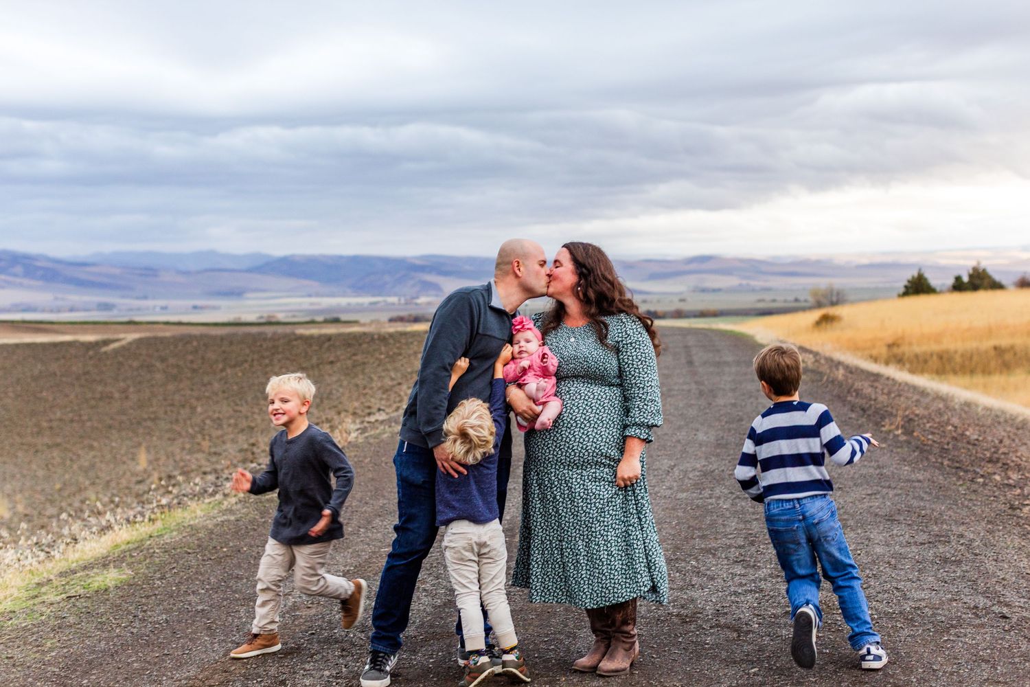 Family members playing and walking together on a scenic mountain path.