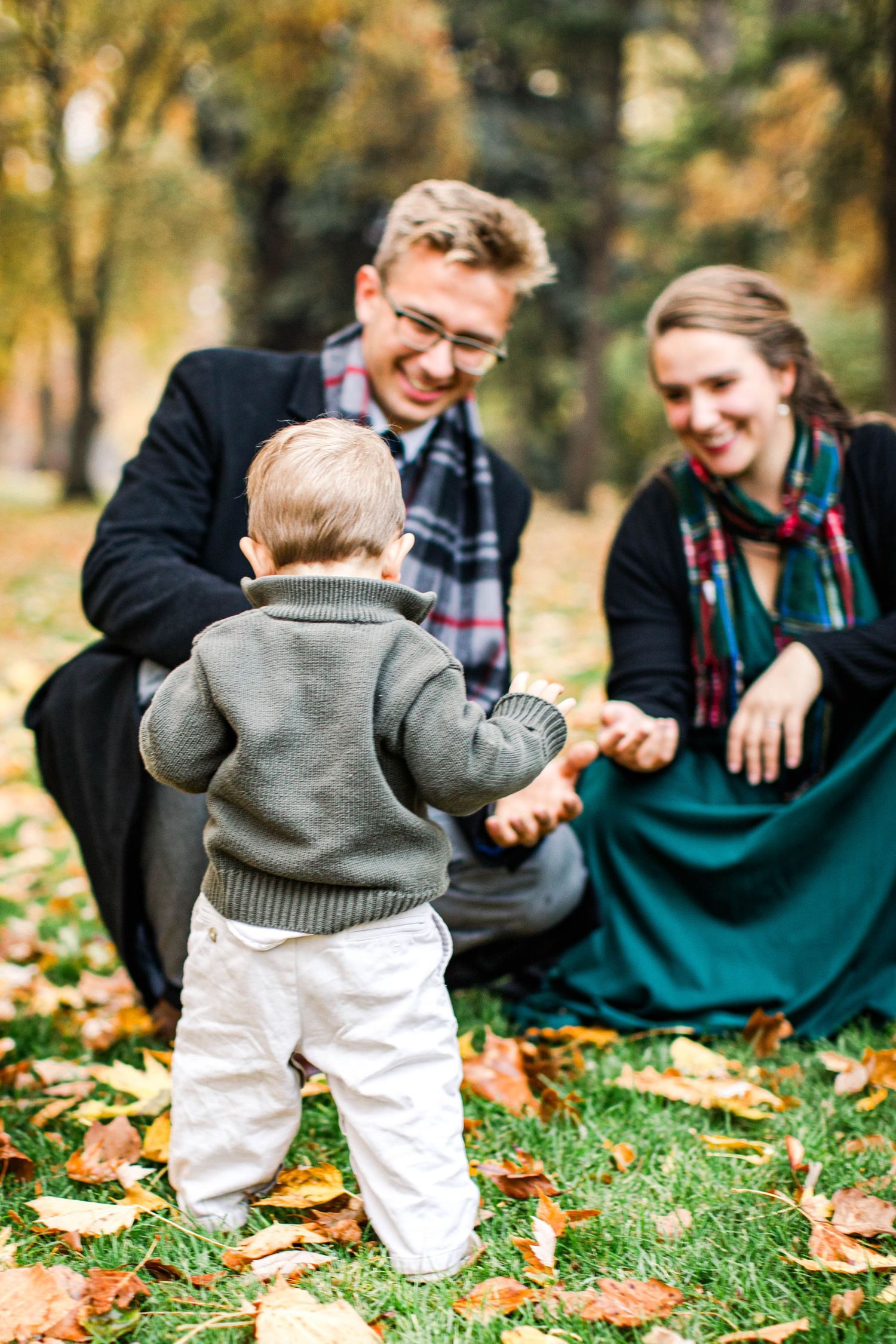 Family enjoying autumn day together on grass covered with fallen leaves.