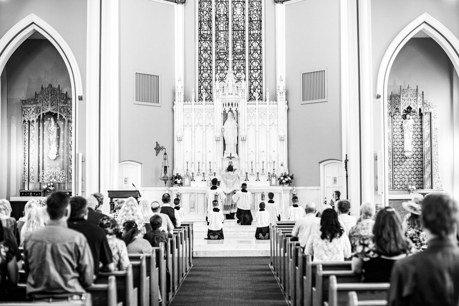 Black and white panorama of a traditional church sanctuary during a wedding service.