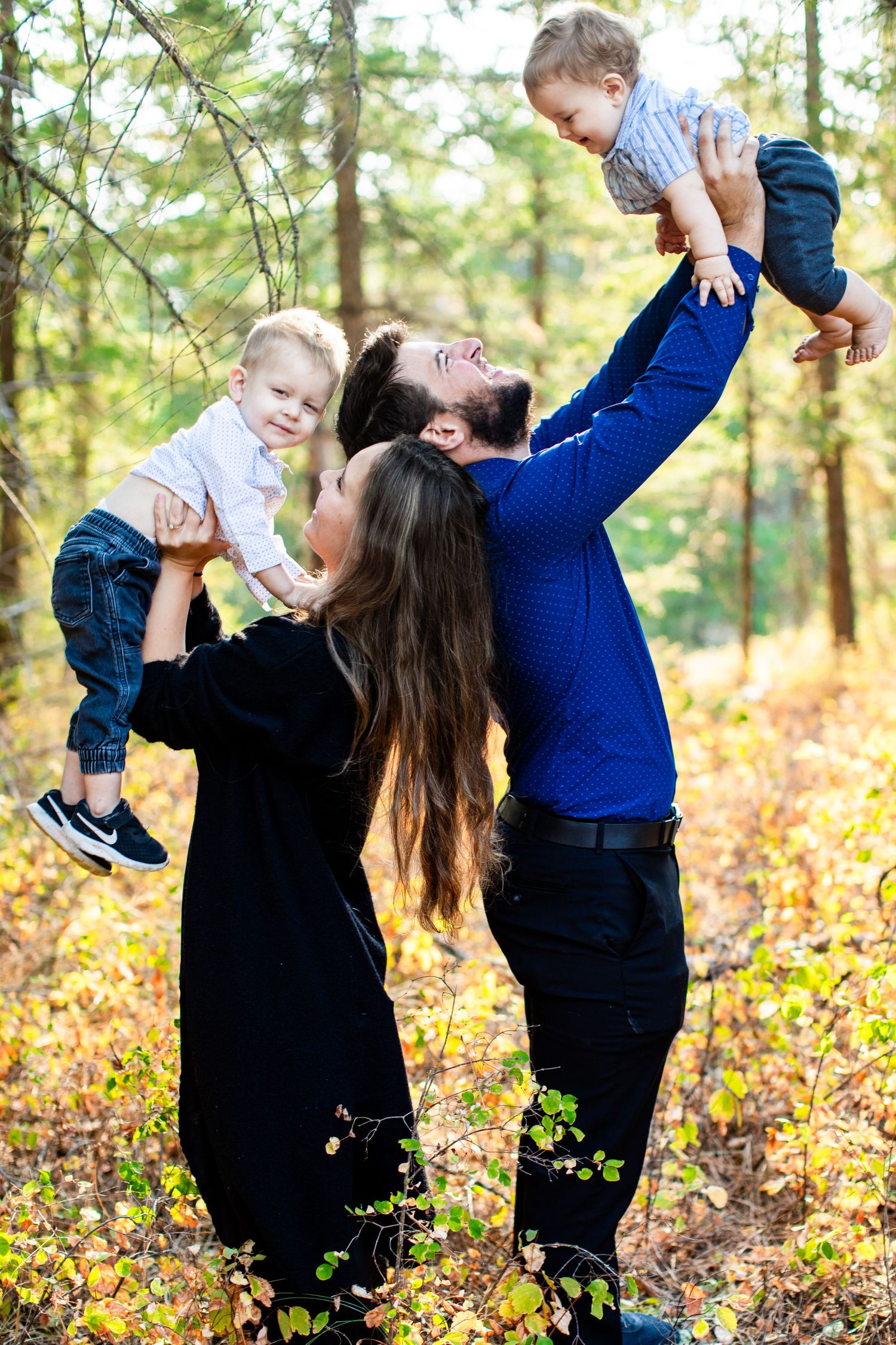 Family playing and laughing together in autumn forest setting.