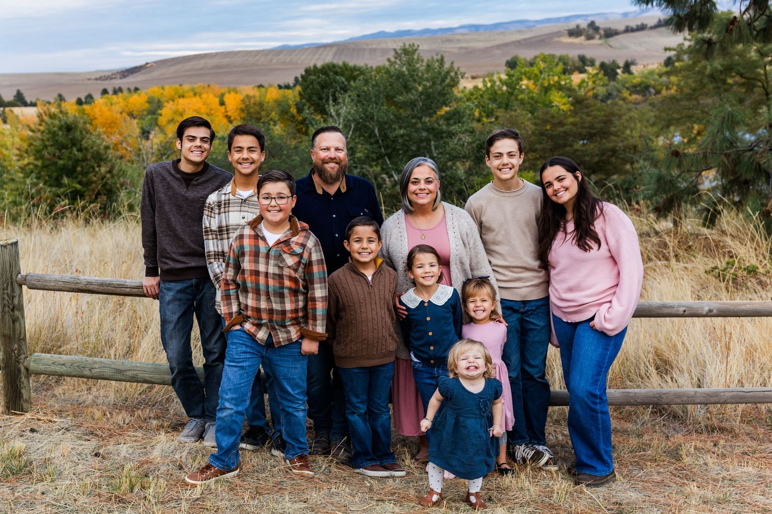 Family photo session outdoors with natural landscape and mountains in background.