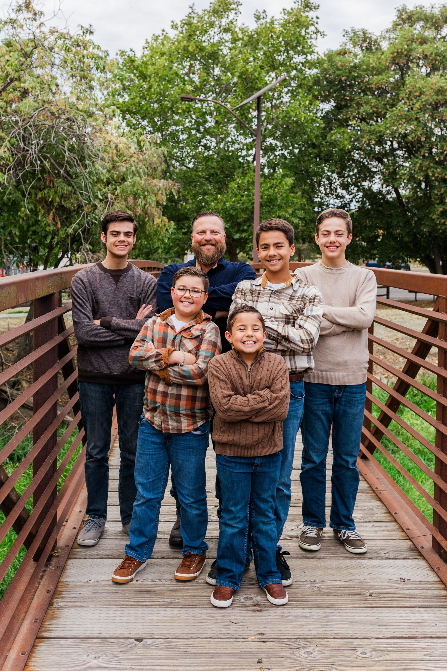 Group portrait of people standing together on a wooden deck with trees in background.