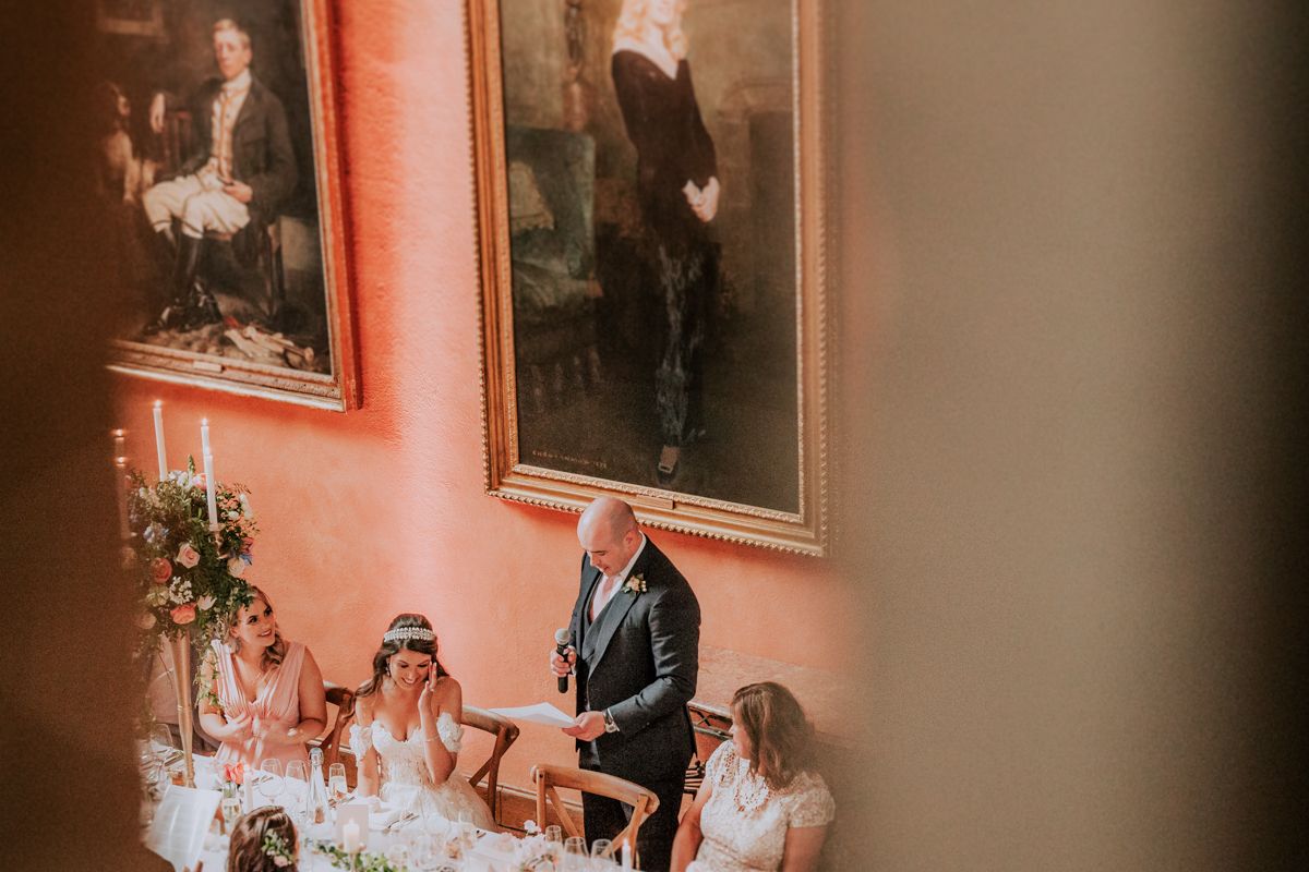 Wedding celebration in a historic venue with coral walls adorned with classic portraits.