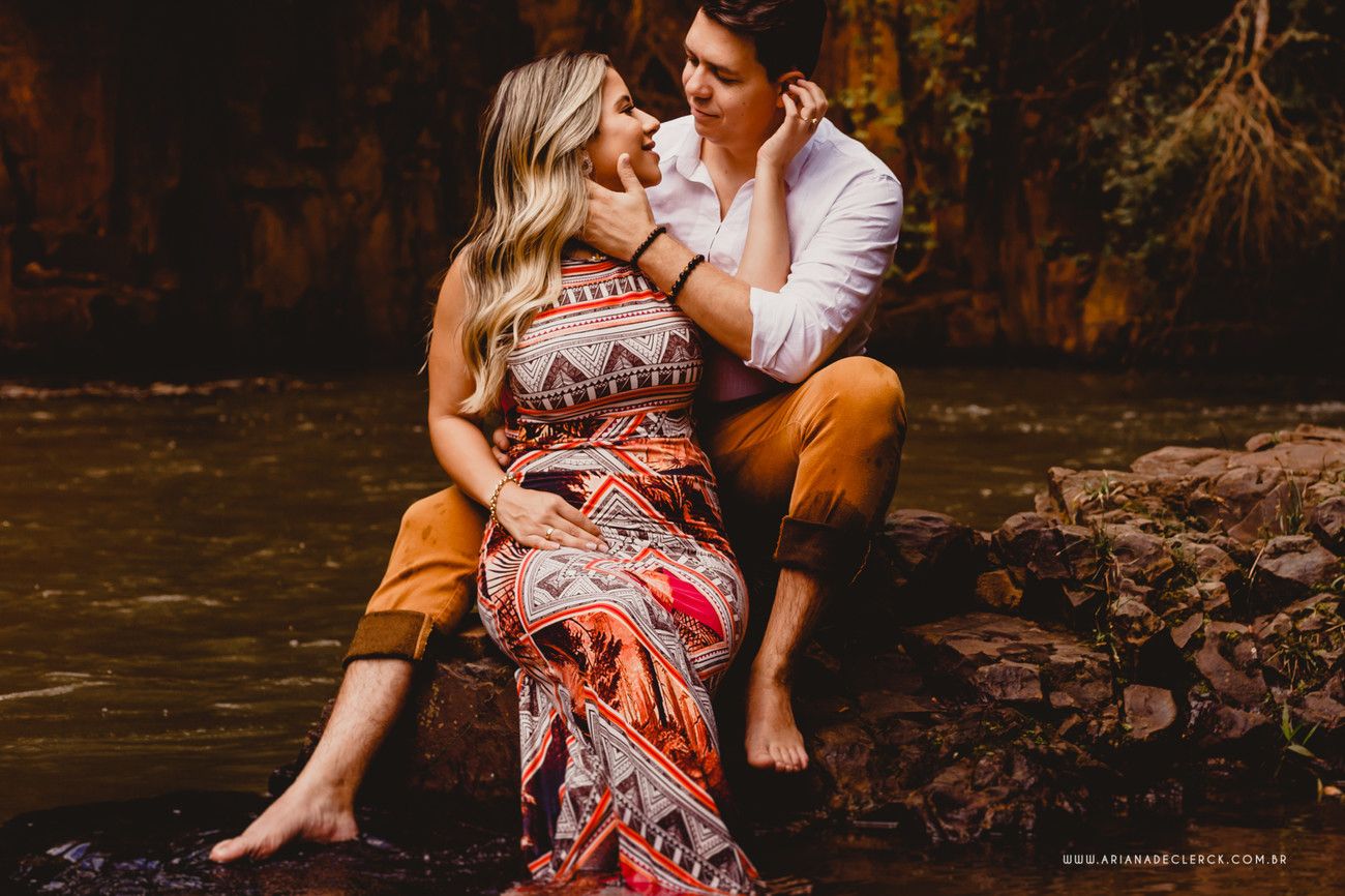 Romantic couple poses by a stream during sunset engagement photo session.
