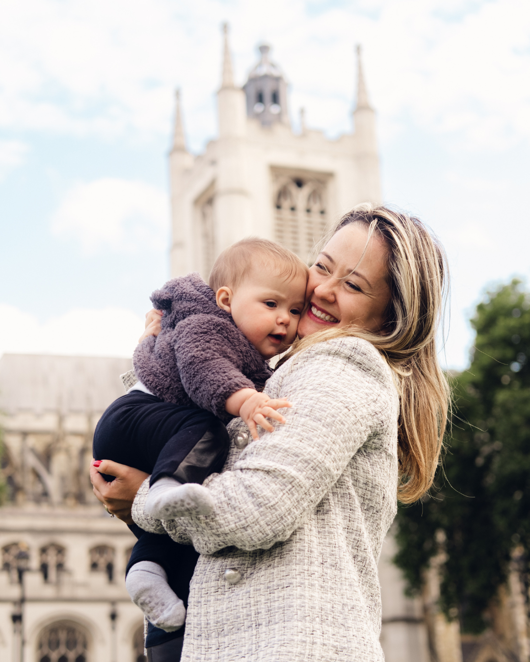 Tender moment captured in front of Gothic church architecture with white stone facade.