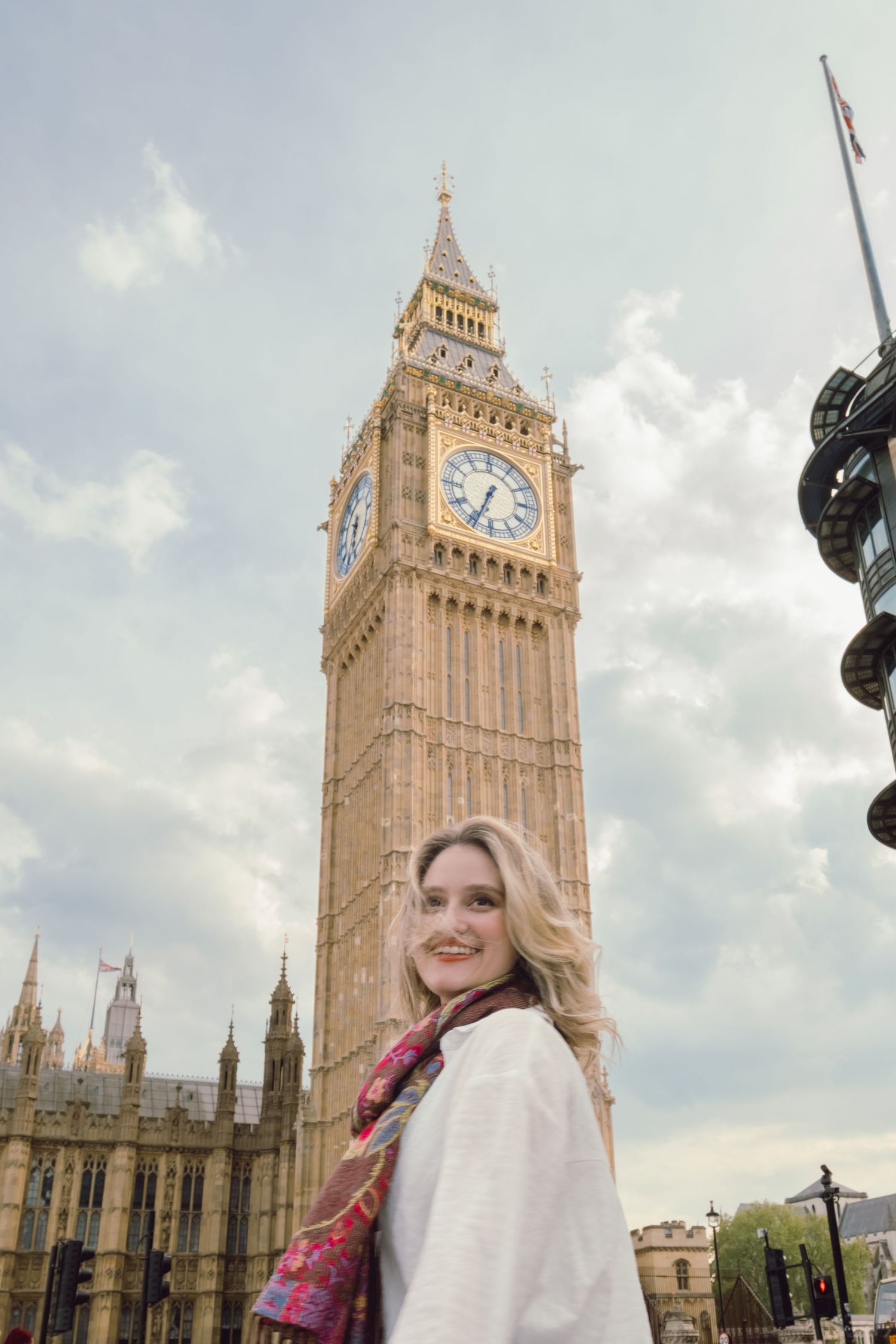 Tourist standing in front of Big Ben and Houses of Parliament on cloudy day.