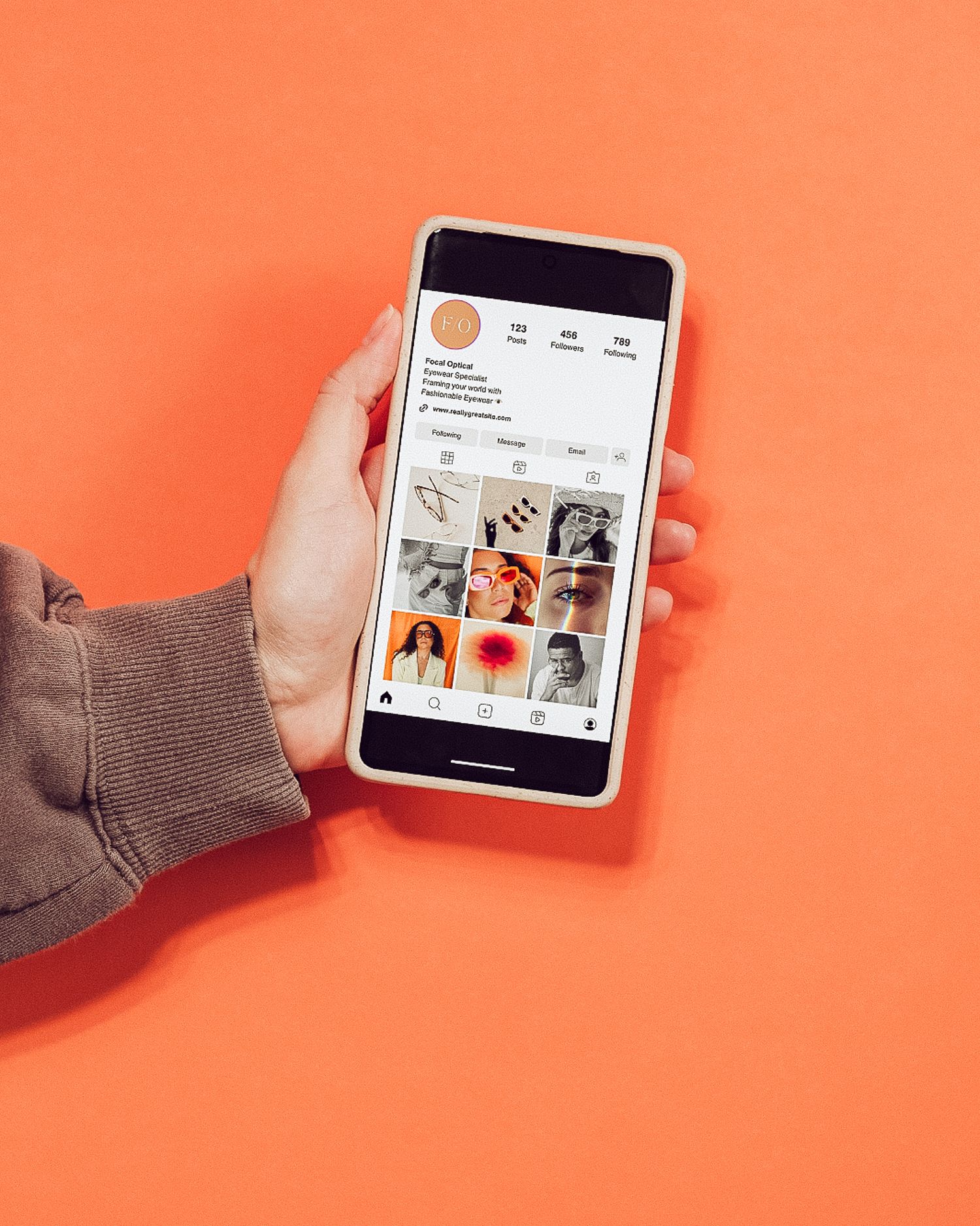 Showcase your brand with a dynamic photoshoot—hand holding a smartphone displaying an Instagram grid against a bold coral orange backdrop.