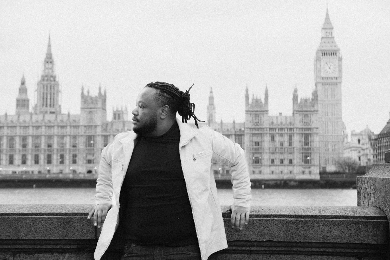 Person in a white jacket poses against London's Houses of Parliament and Big Ben backdrop.