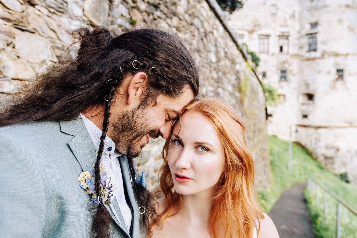 Intimate portrait of couple near historic stone architecture.