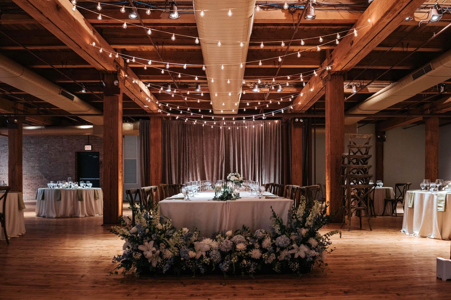 Rustic wedding venue with exposed wooden beams and romantic string lighting overhead.