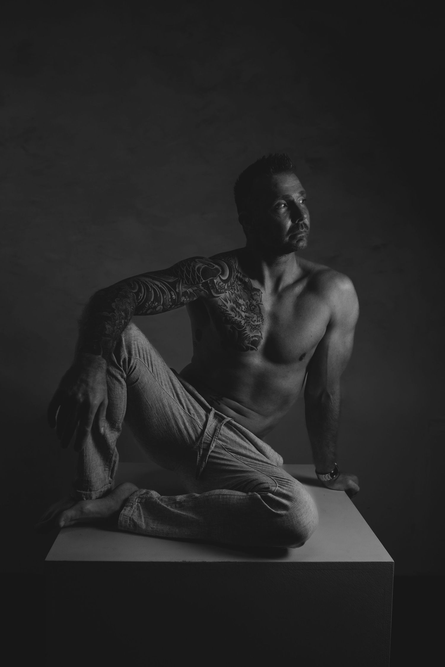 Zwart/wit foto van een dudeoir fotoshoot van een man met een broek aan en een blote bovenlijf