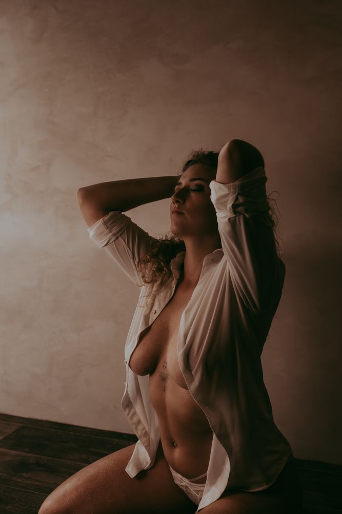An artistic boudoir photography series featuring dramatic shadows and intimate poses against a dark wall.