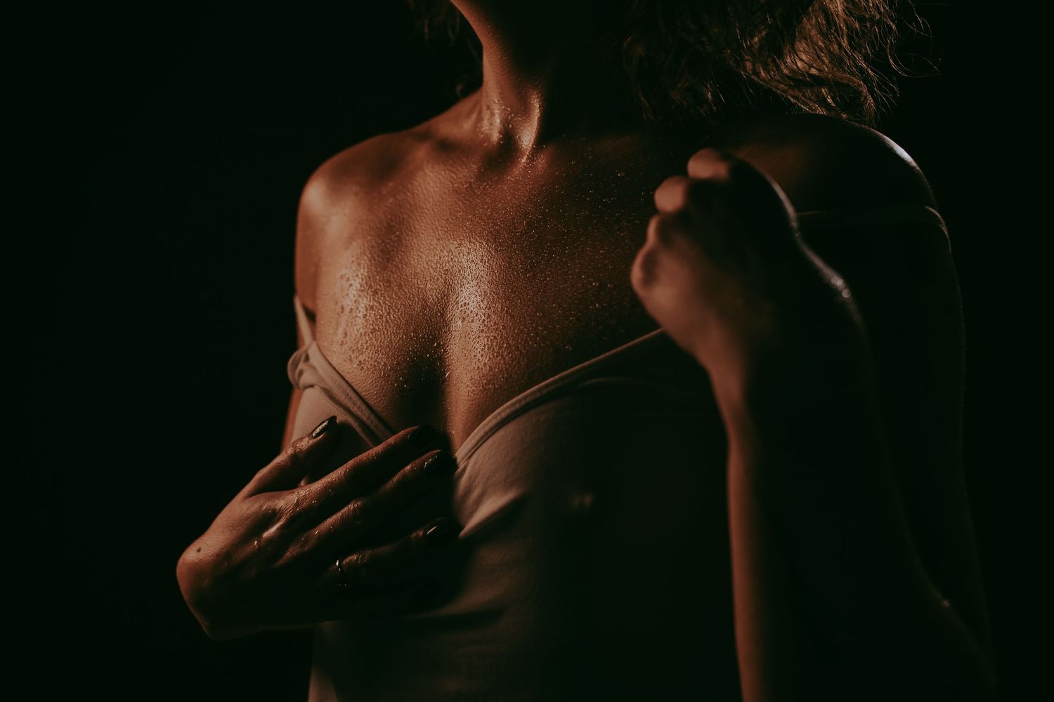 Close-up of a person's bare back and shoulders in dramatic low-key lighting, highlighting skin texture.