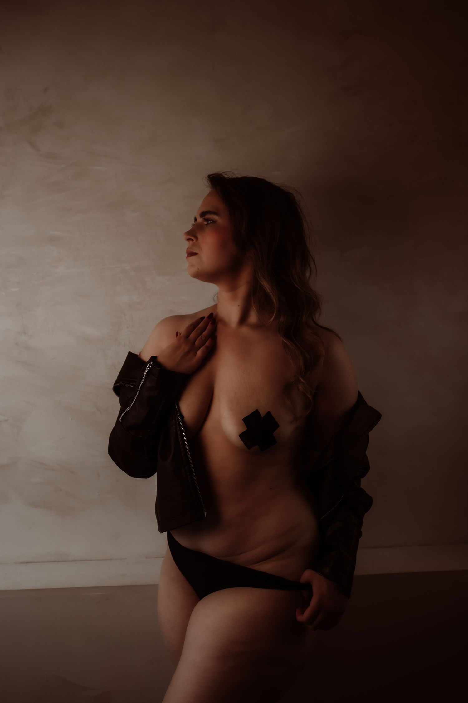 Artistieke boudoir fotografie met vrouw en geplakte tepelcover en een zwart stoer jasje