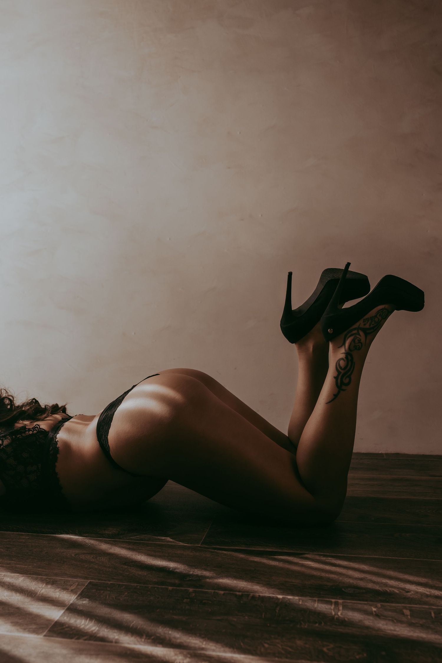 liggende vrouw met een zwarte lingerie set en zwarte hoge hakken draagt geposeerd met de billen omhoog