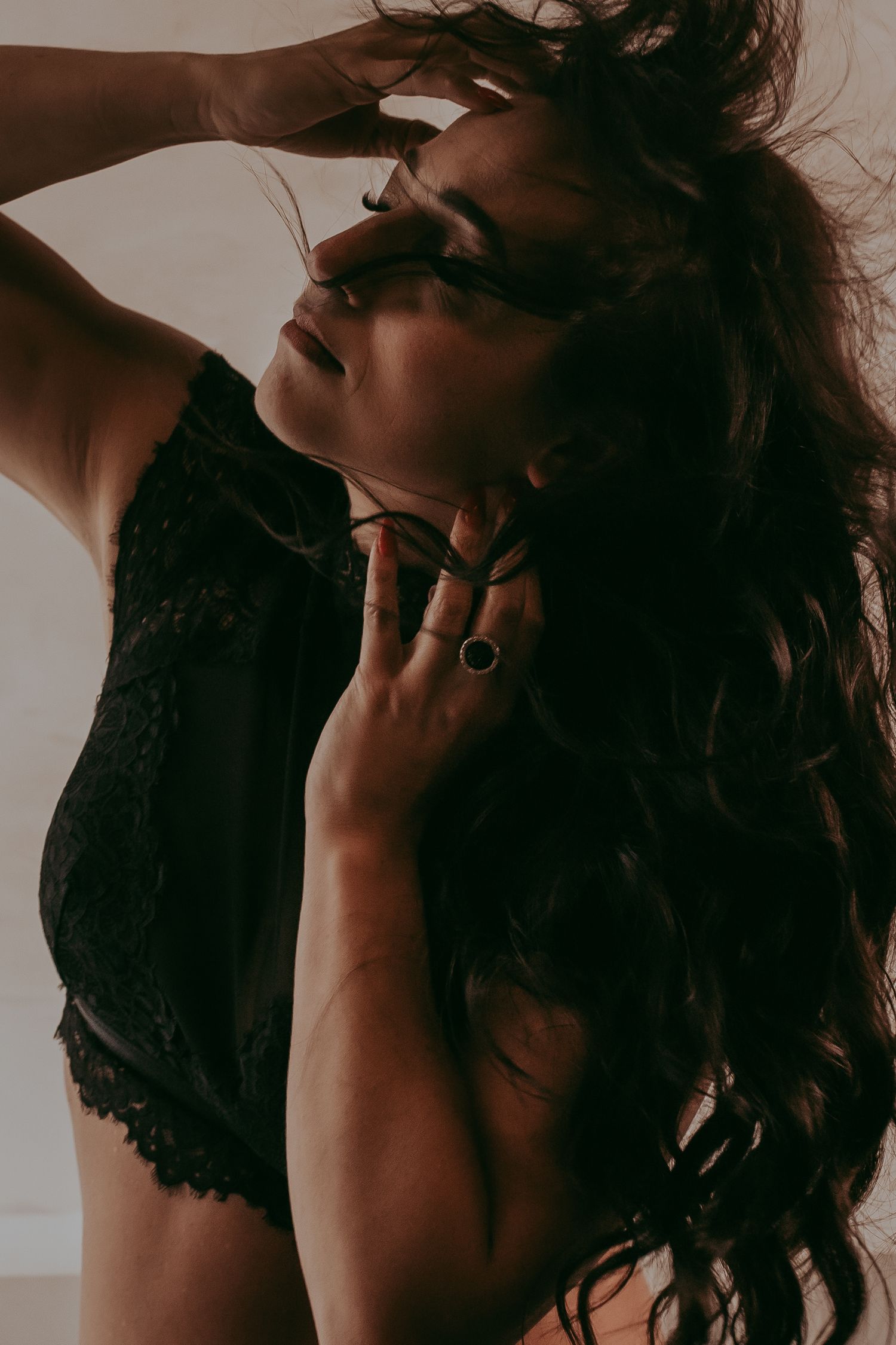 Artistieke foto van een vrouw met wapperende haren en een zwarte lingerie setje aan met lange bruine haren