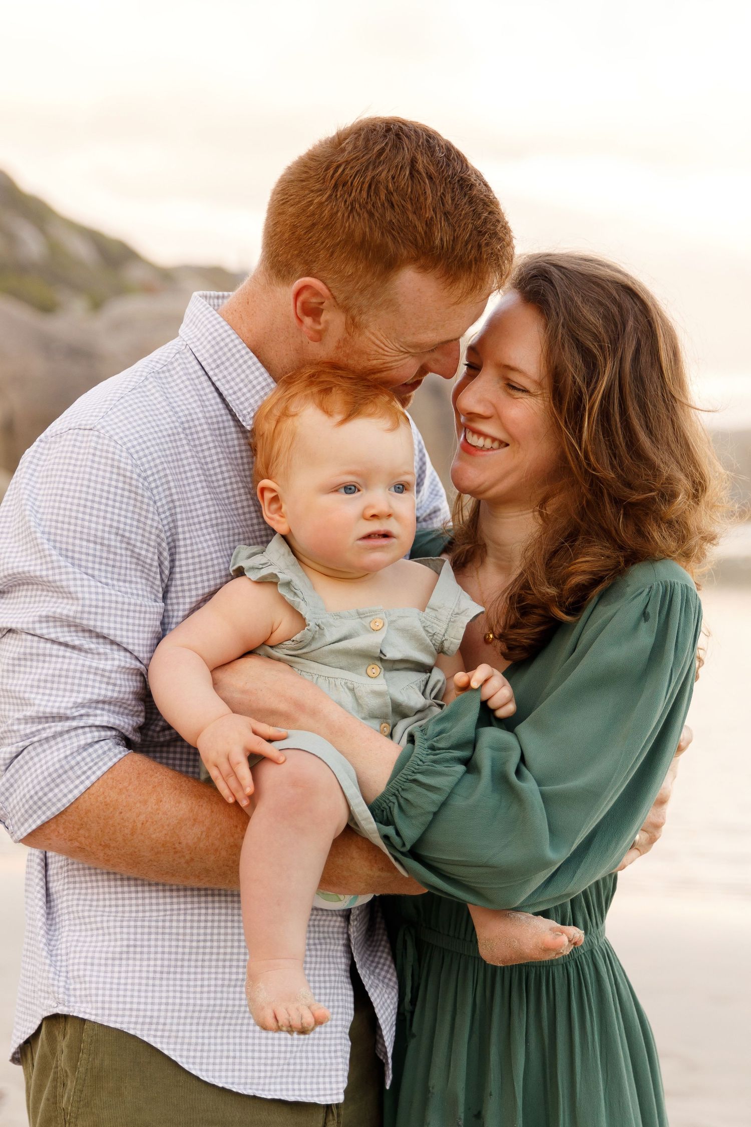 A loving family embraces together on the beach at sunset with warm lighting creating a tender moment.