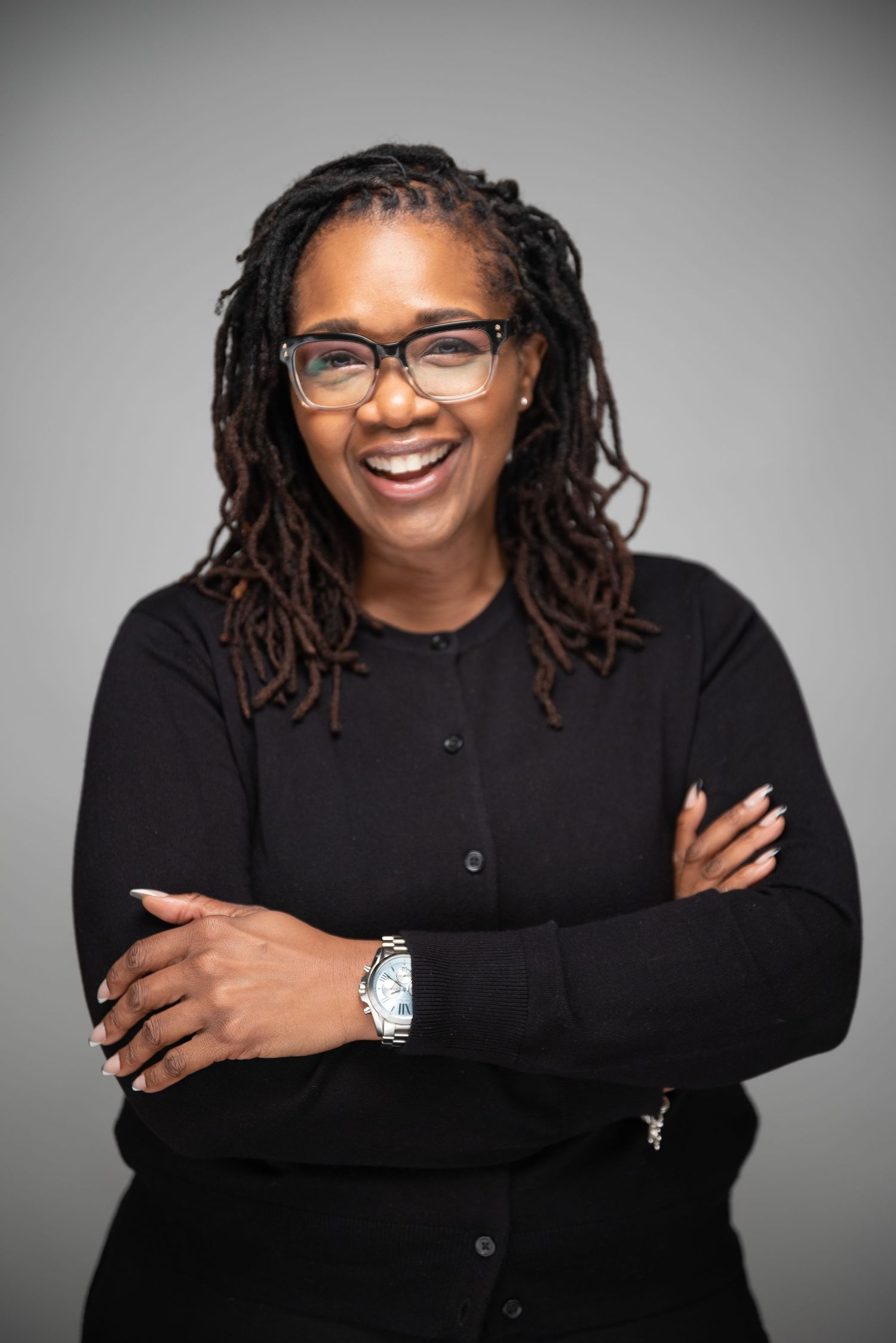 Professional headshots against grey background showing warm expressions and natural locs hairstyle.