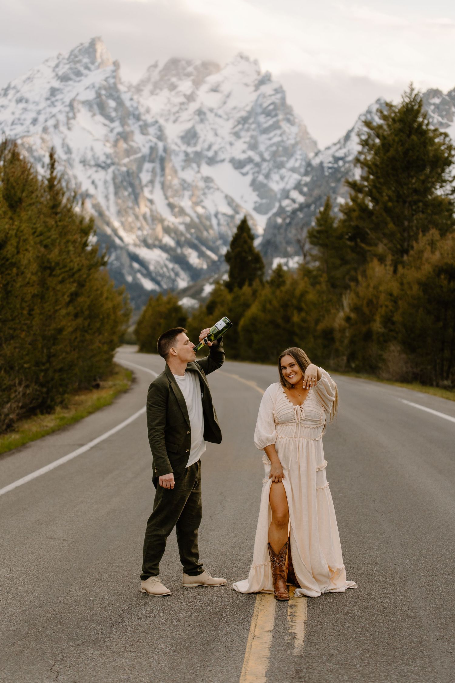 Couple on mountain road with snowy peaks in background.