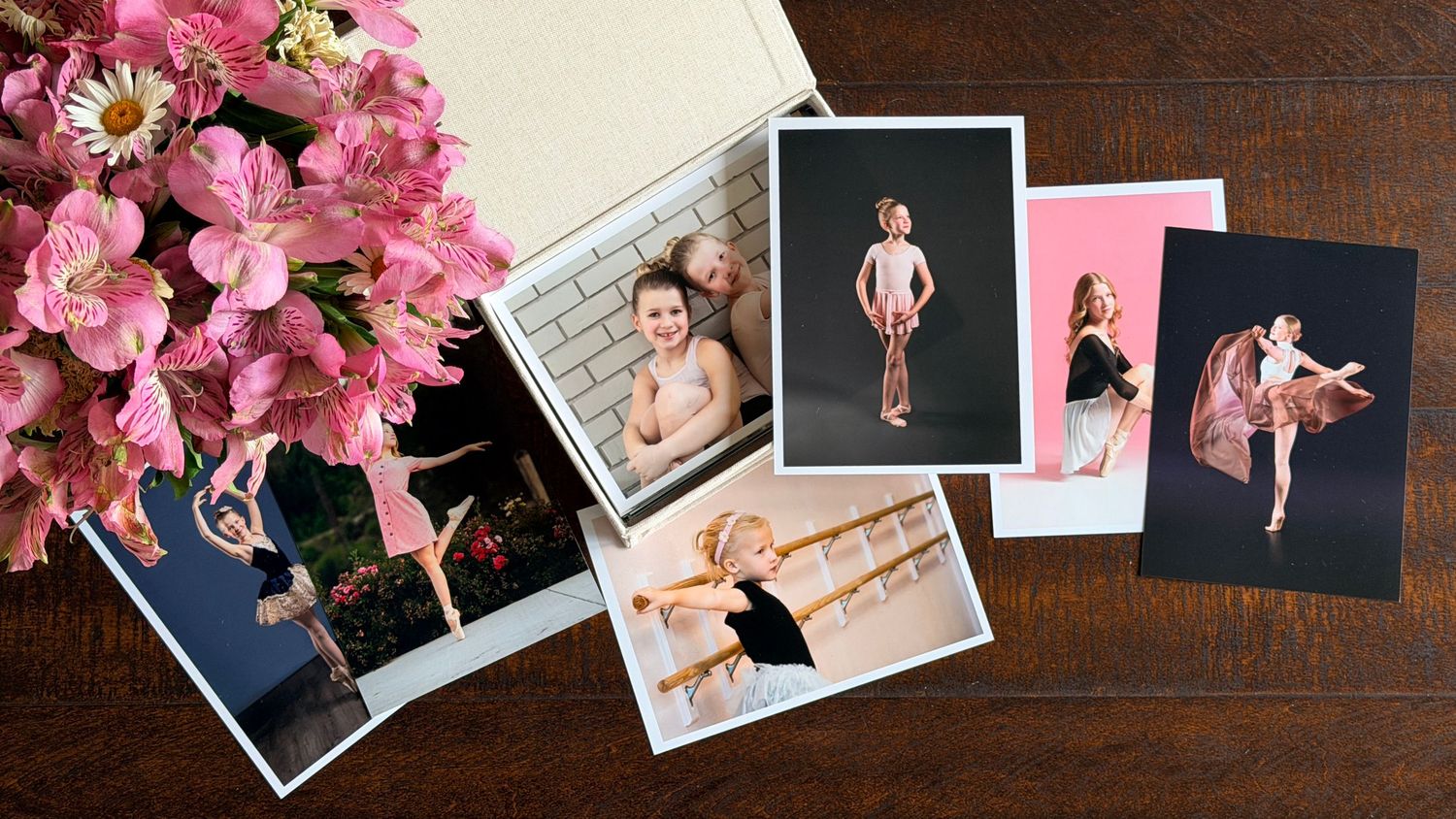 Ballet dance photos spread on wooden table with pink flowers, featuring children and adults in various dance poses.
