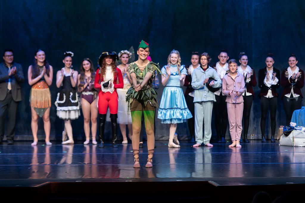 Peter Pan ballet cast takes final bow on stage with full ensemble in colorful costumes.