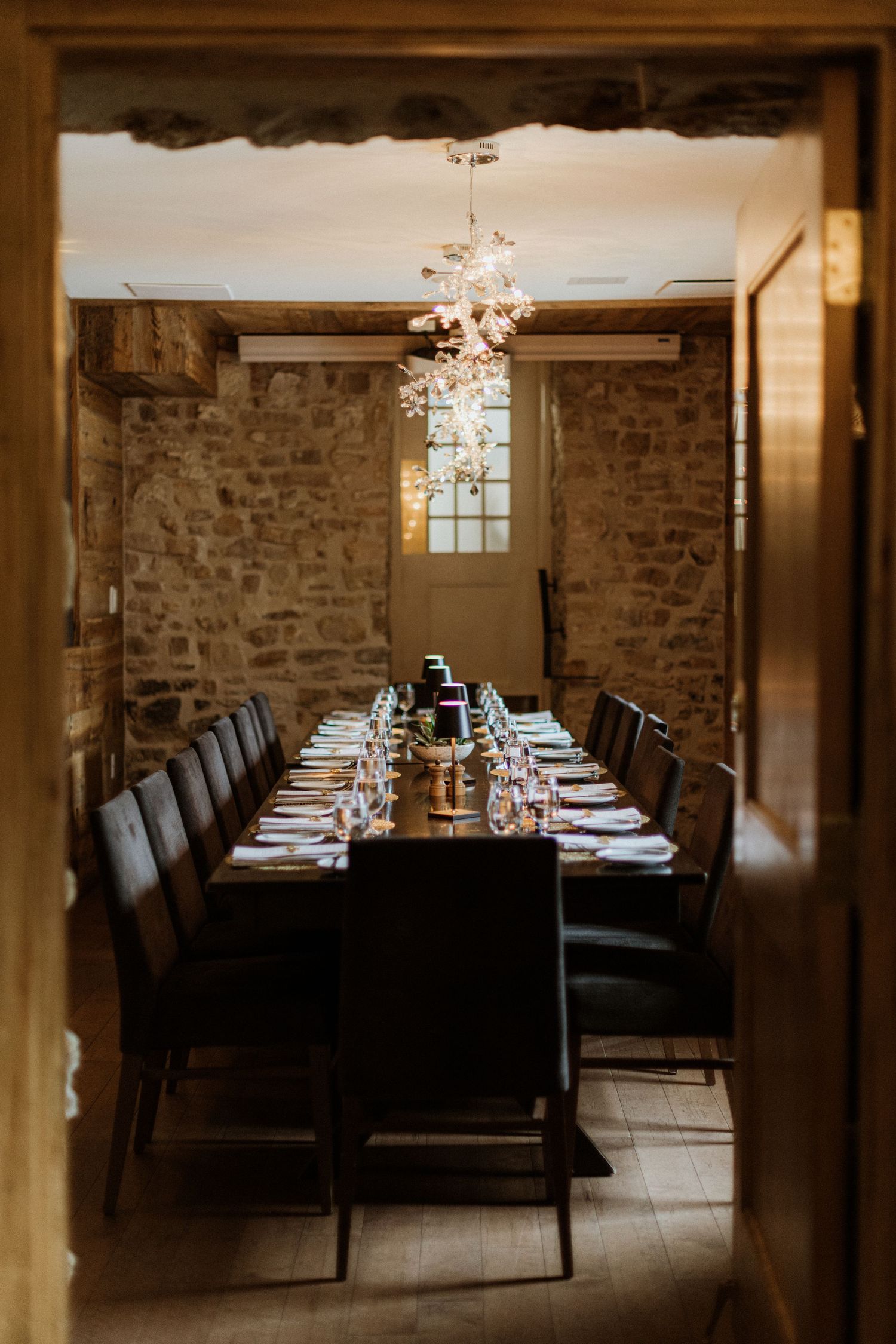 Intimate private dining room with long table set for wedding dinner viewed through doorway.