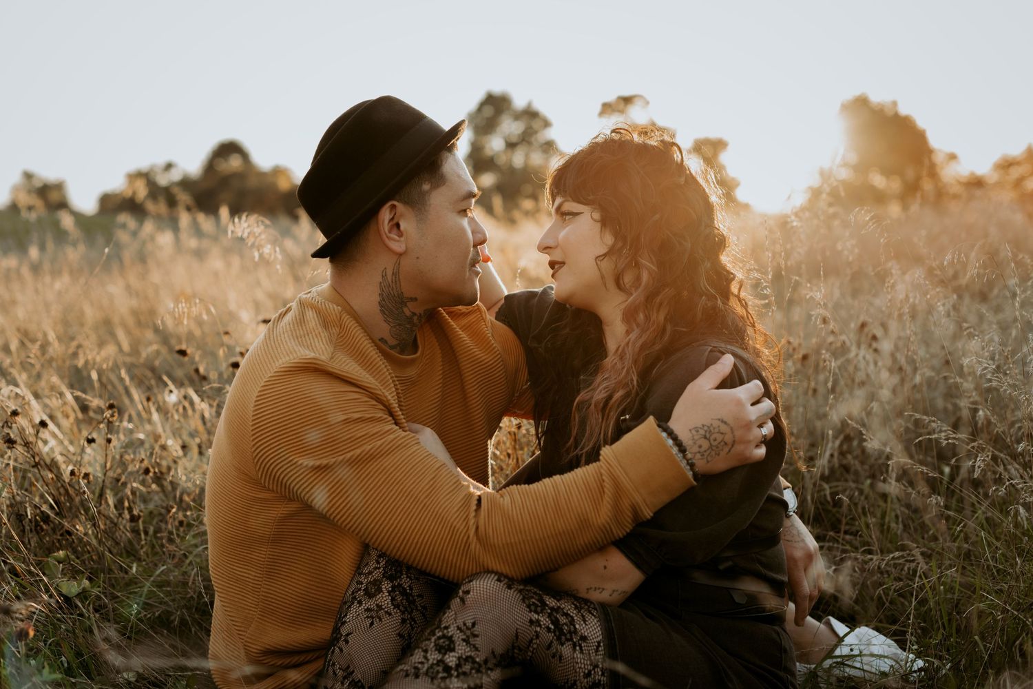 Romantic couple embracing in a golden field at sunset with warm glowing light.