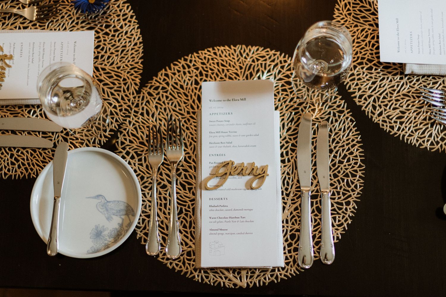 Wedding place setting with gold charger, white plate, menu card and laser-cut name card.