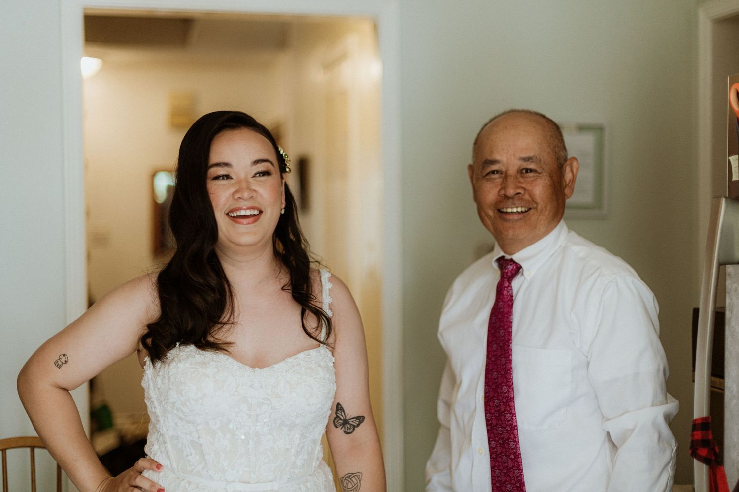 Bride in lace wedding gown smiling with older man in white shirt and burgundy tie.