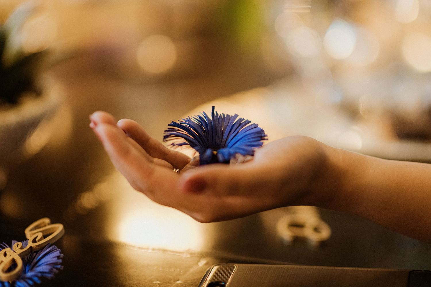 Hand holding a delicate blue flower tassel decoration at a wedding reception.