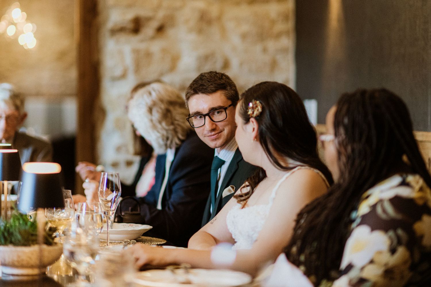 Bride and groom share an intimate moment at their wedding reception dinner table with guests.