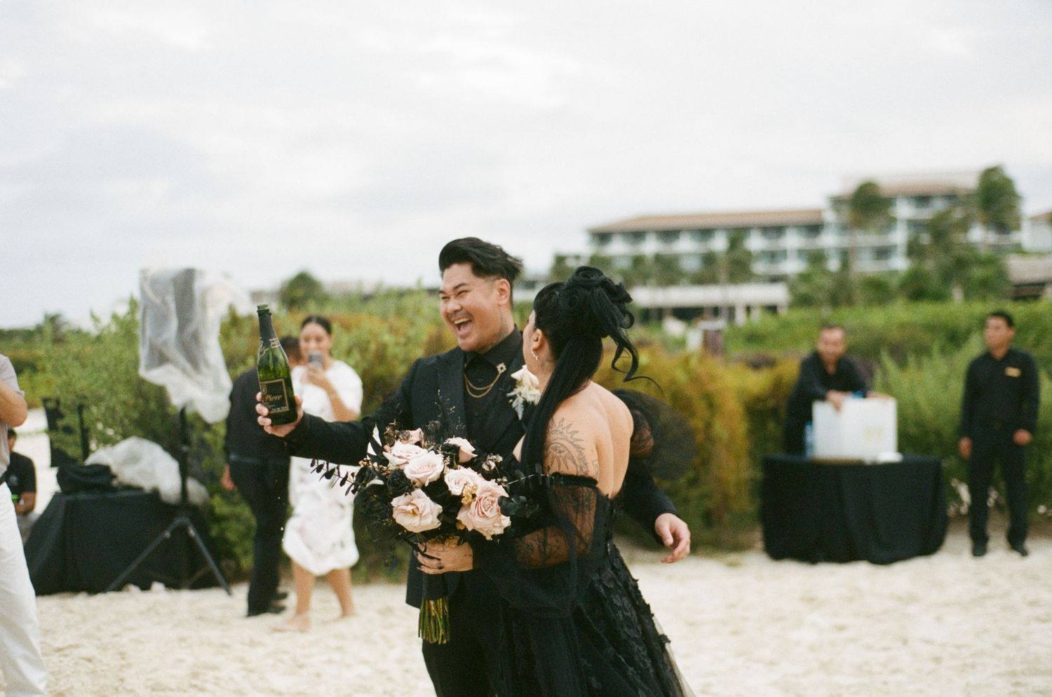 Newlyweds laugh joyfully during outdoor beach wedding celebration.