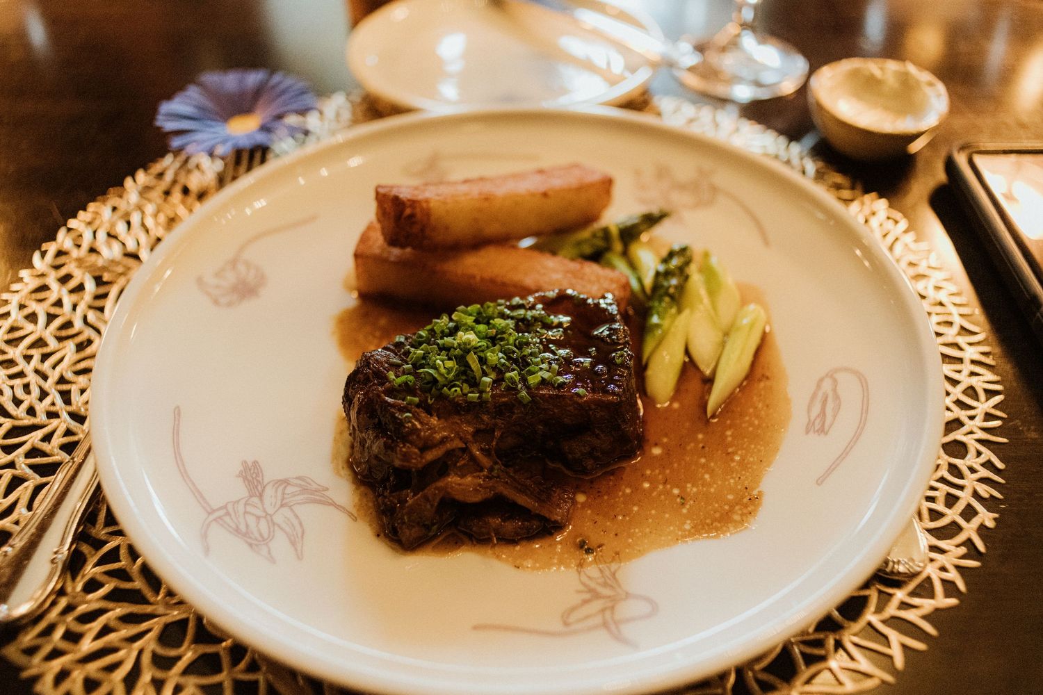 Elegant plated wedding dinner dish featuring braised beef short rib with asparagus and herb garnish.